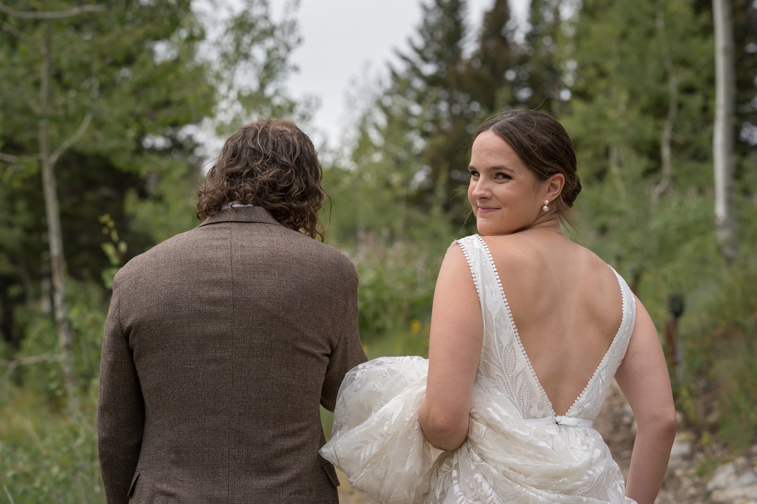 Documentary style wedding photography, bride looking back at photographer over shoulder, Grand Targhee Resort