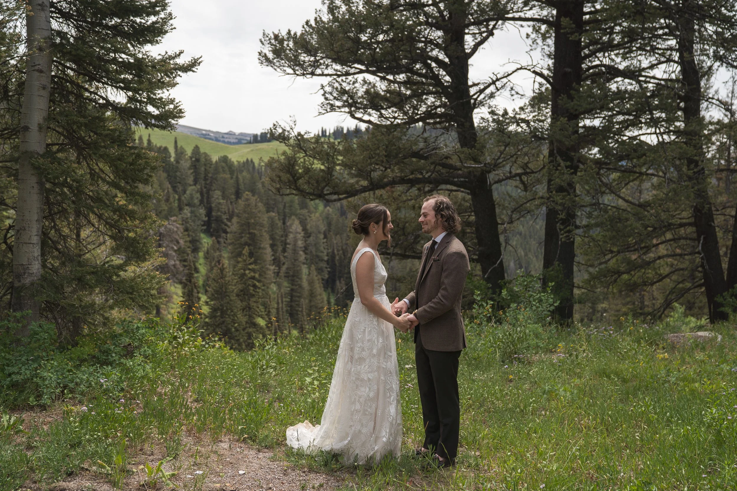 Bride and Groom's first look at Grand Targhee resort, standing in forest holding hands, documentary style photography