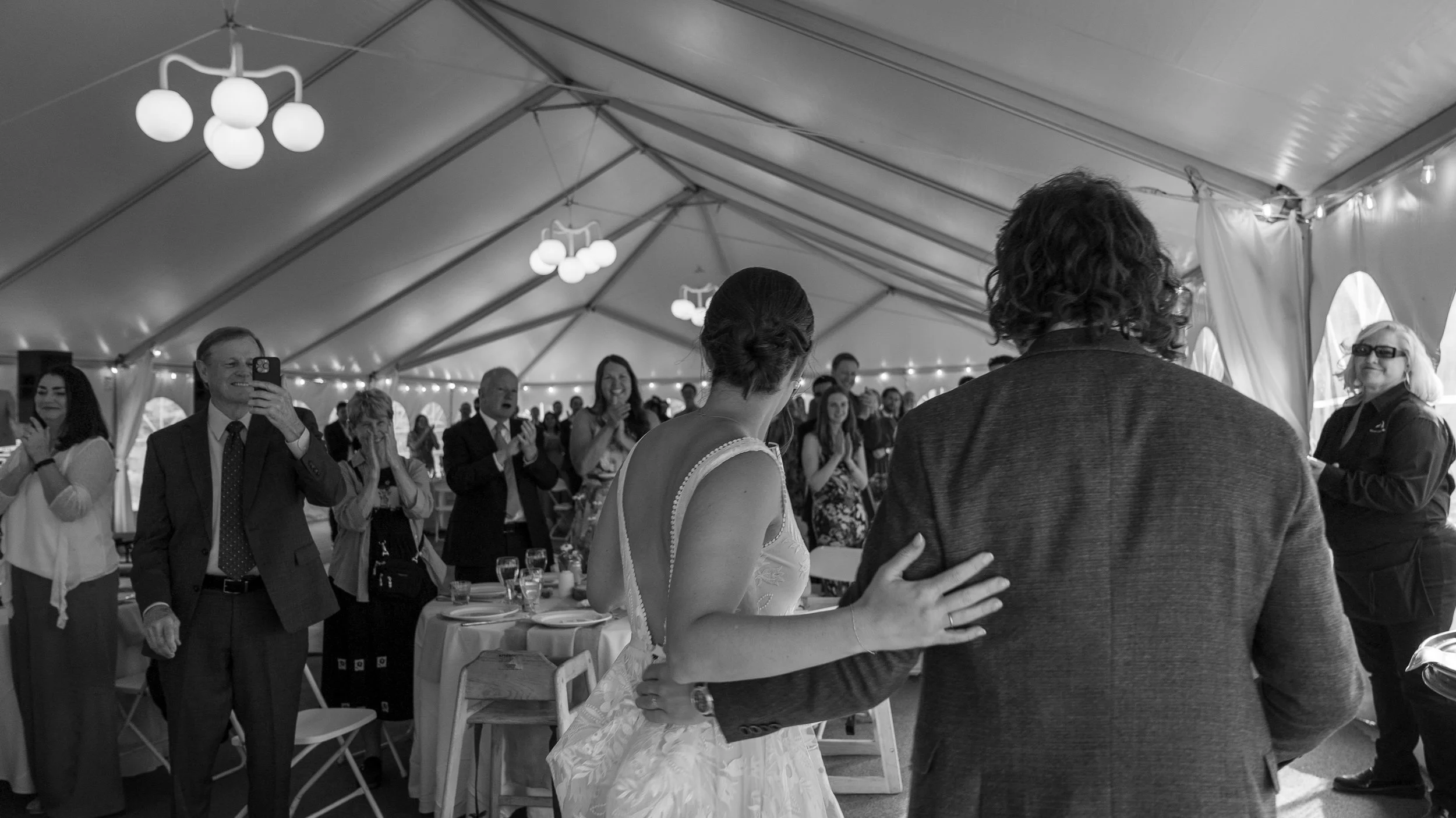 Grand Targhee Resort, documentary Wedding photography; bride and groom facing away from the camera with guests in the background cheering on