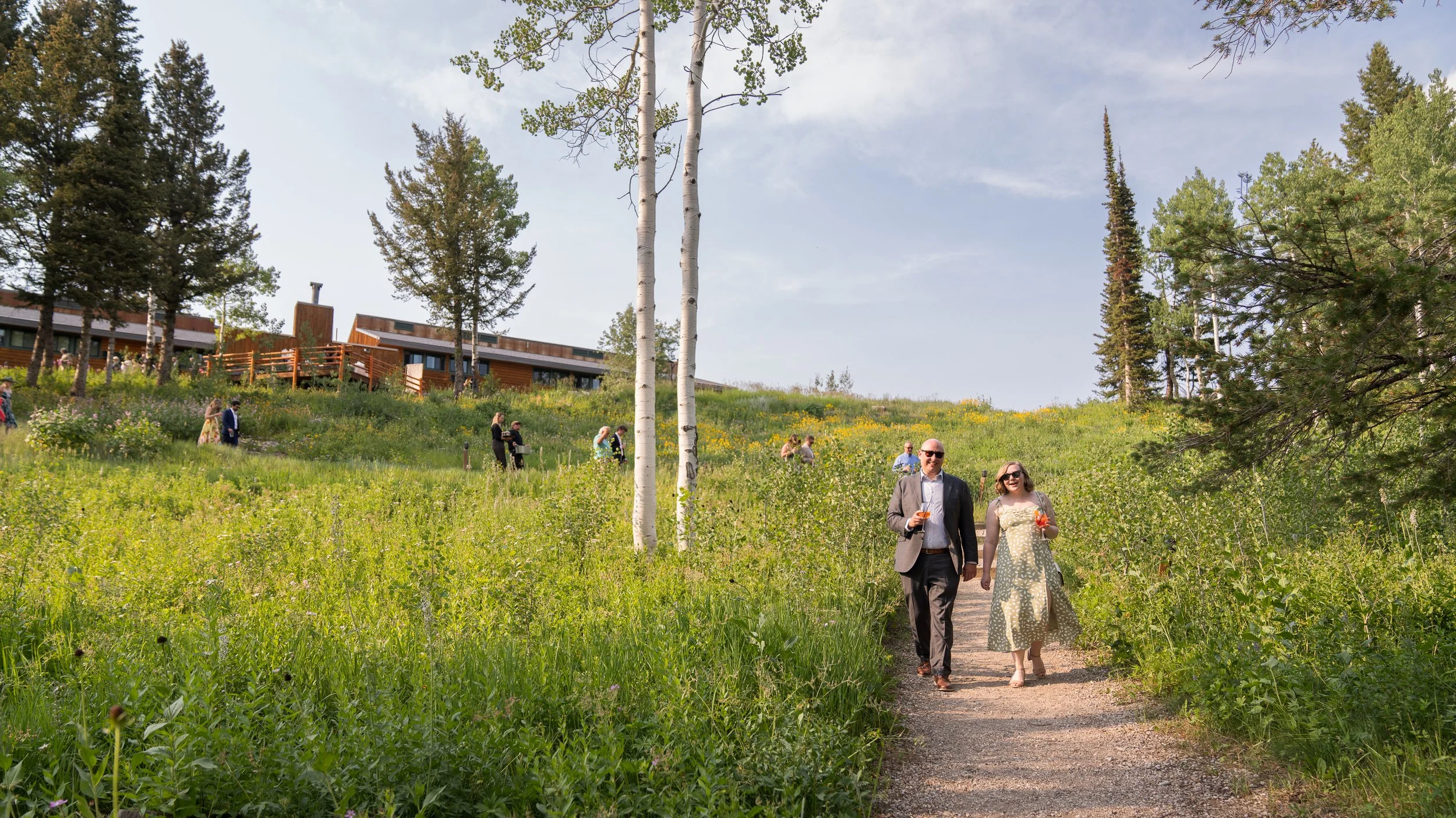 Grand Targhee Resort, documentary Wedding photography; family and friends walking path from ceremony site to reception tent, aspen trees and wildflower field