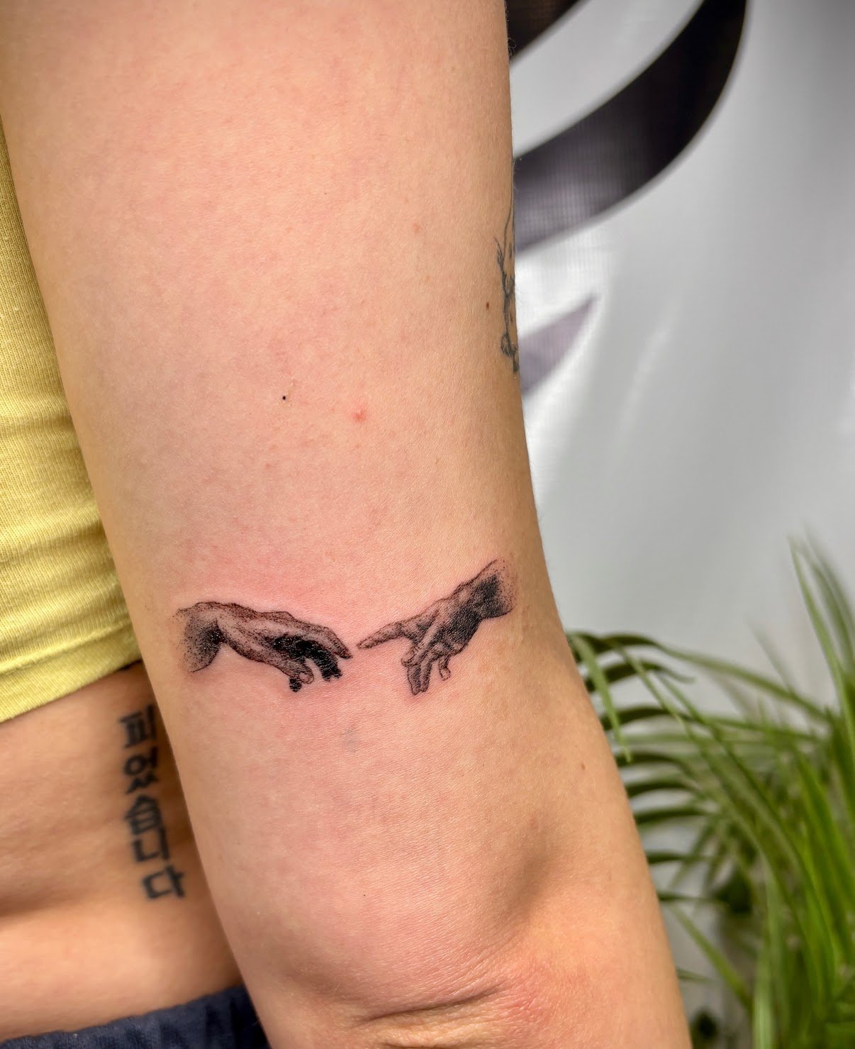 Tattoo of two hands reaching towards each other on a person's inner forearm.