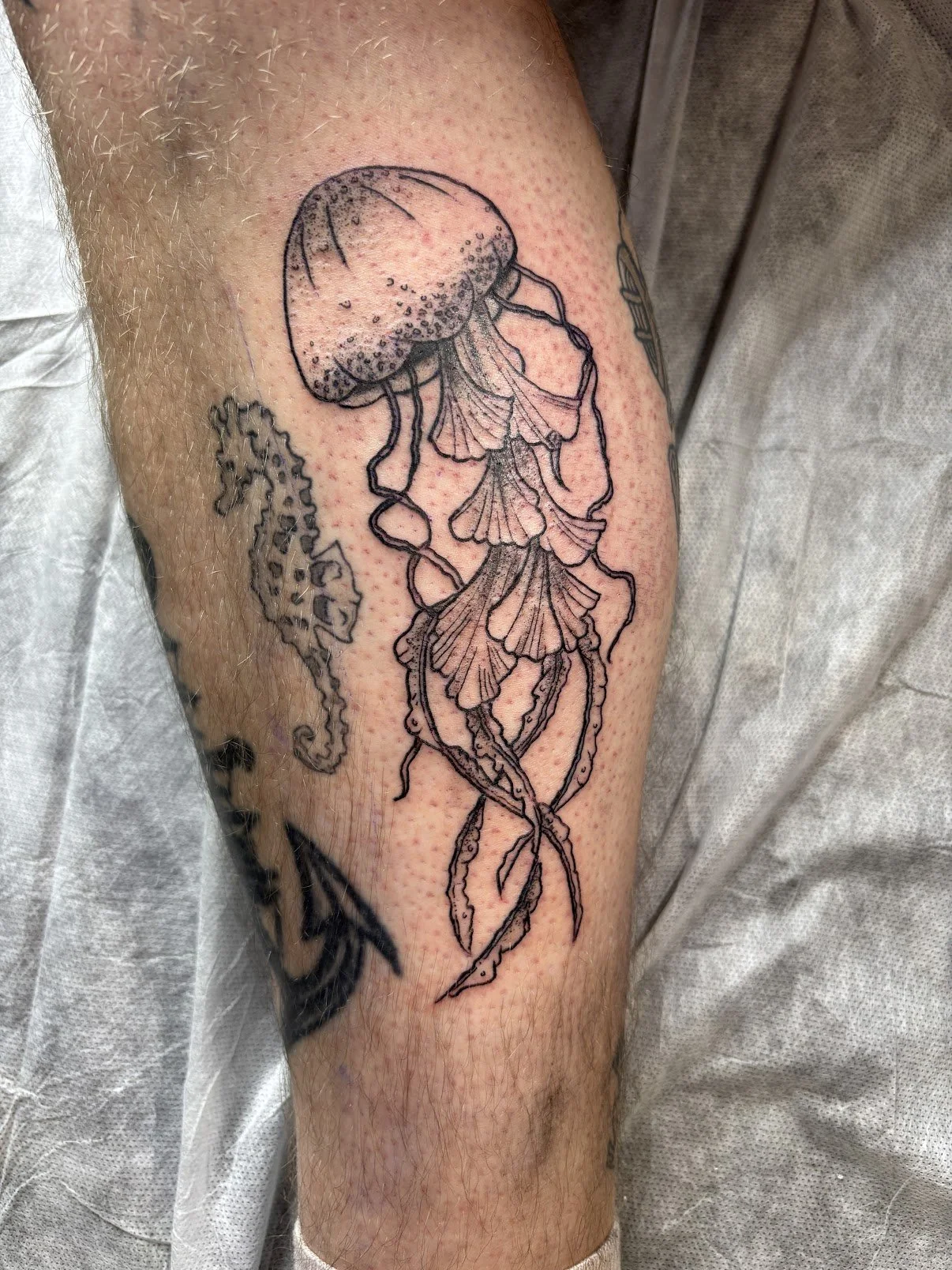 Black outline tattoo of a jellyfish on a person's arm.