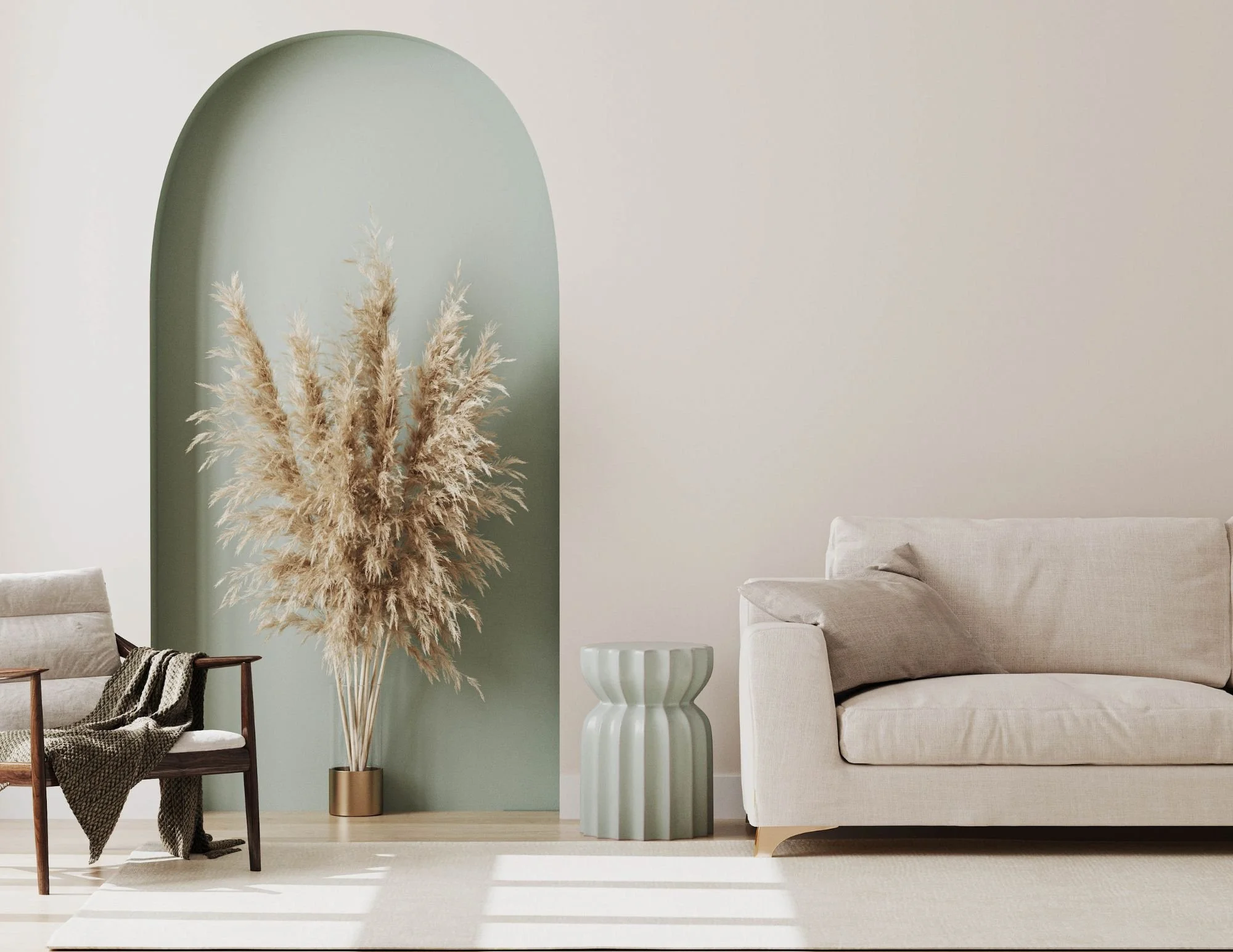 Minimalist living room with a beige sofa, a small greenish side table, and a tall vase with pampas grass against a wall with an arch-shaped cutout.