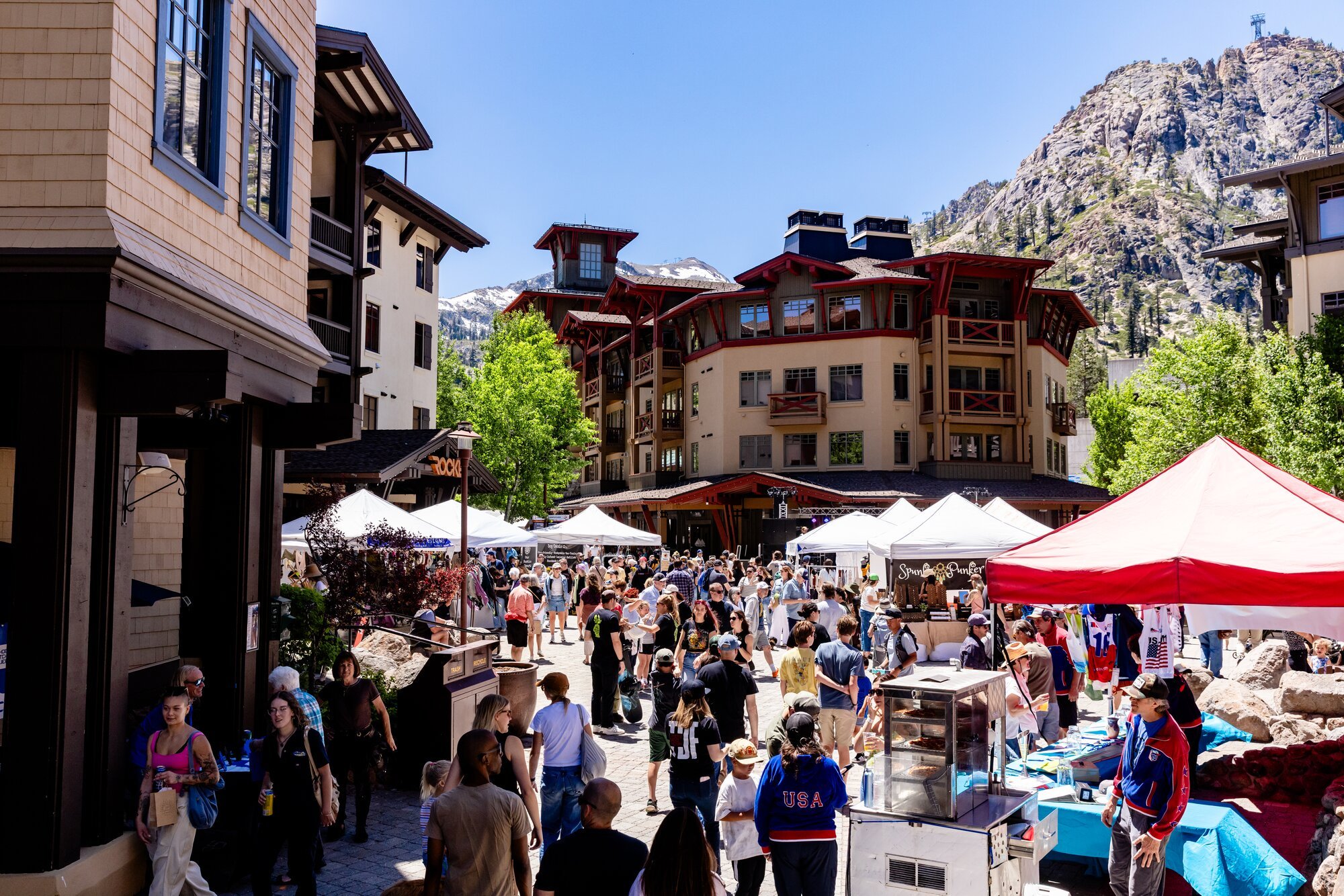 Visitors browse vendor tents beneath the rocky mountain face at the Village at Palisades Tahoe.