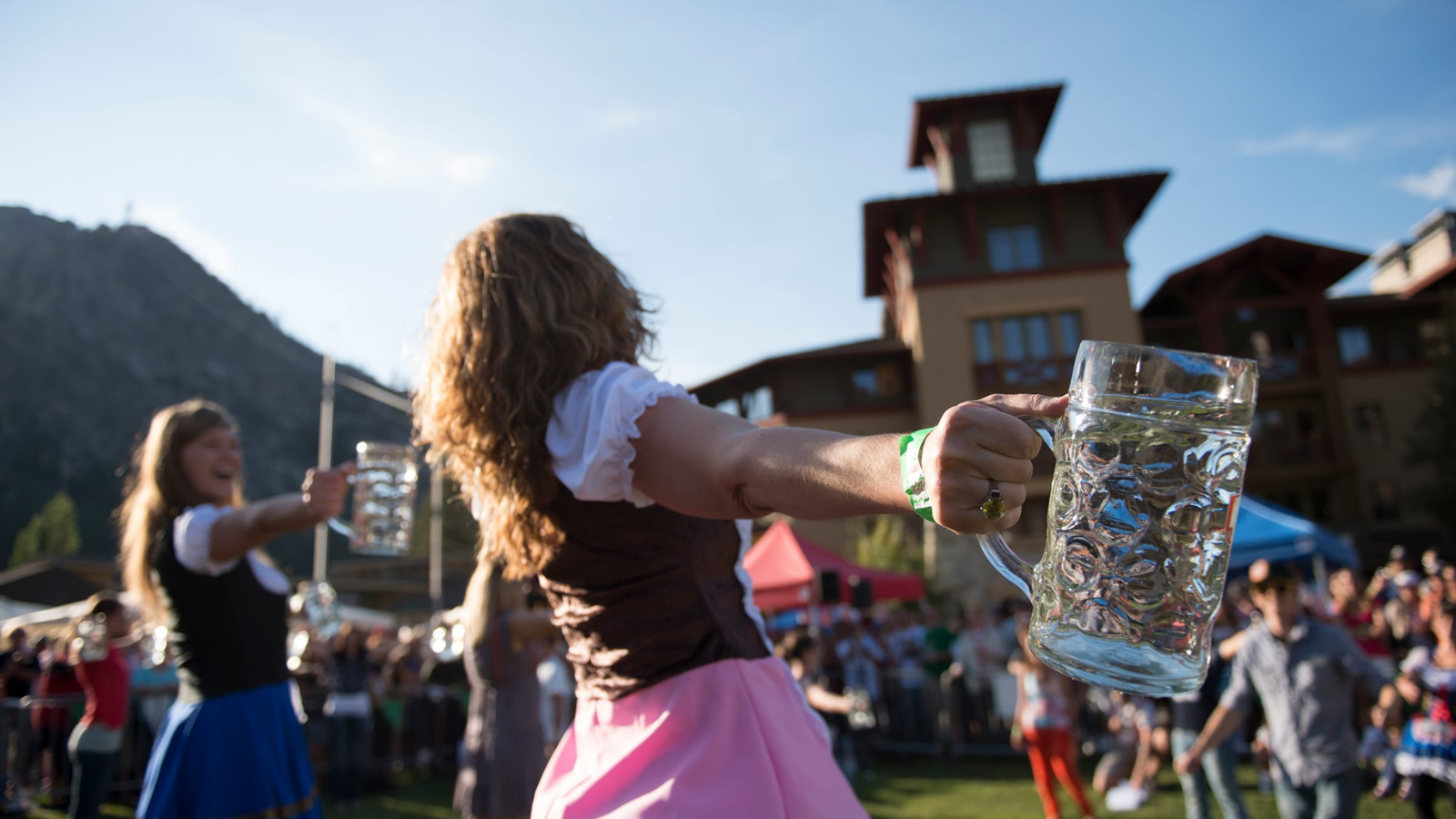 Women in dirndls hold steins during an Oktoberfest competition at The Village at Palisades Tahoe.