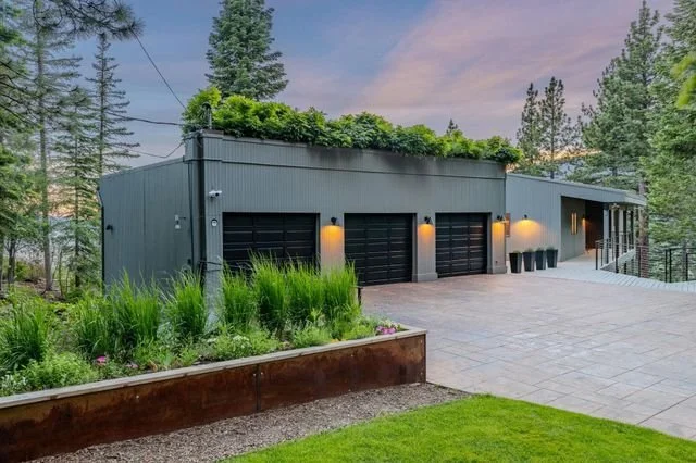 Detached garage with a green living roof, photographed at dusk.