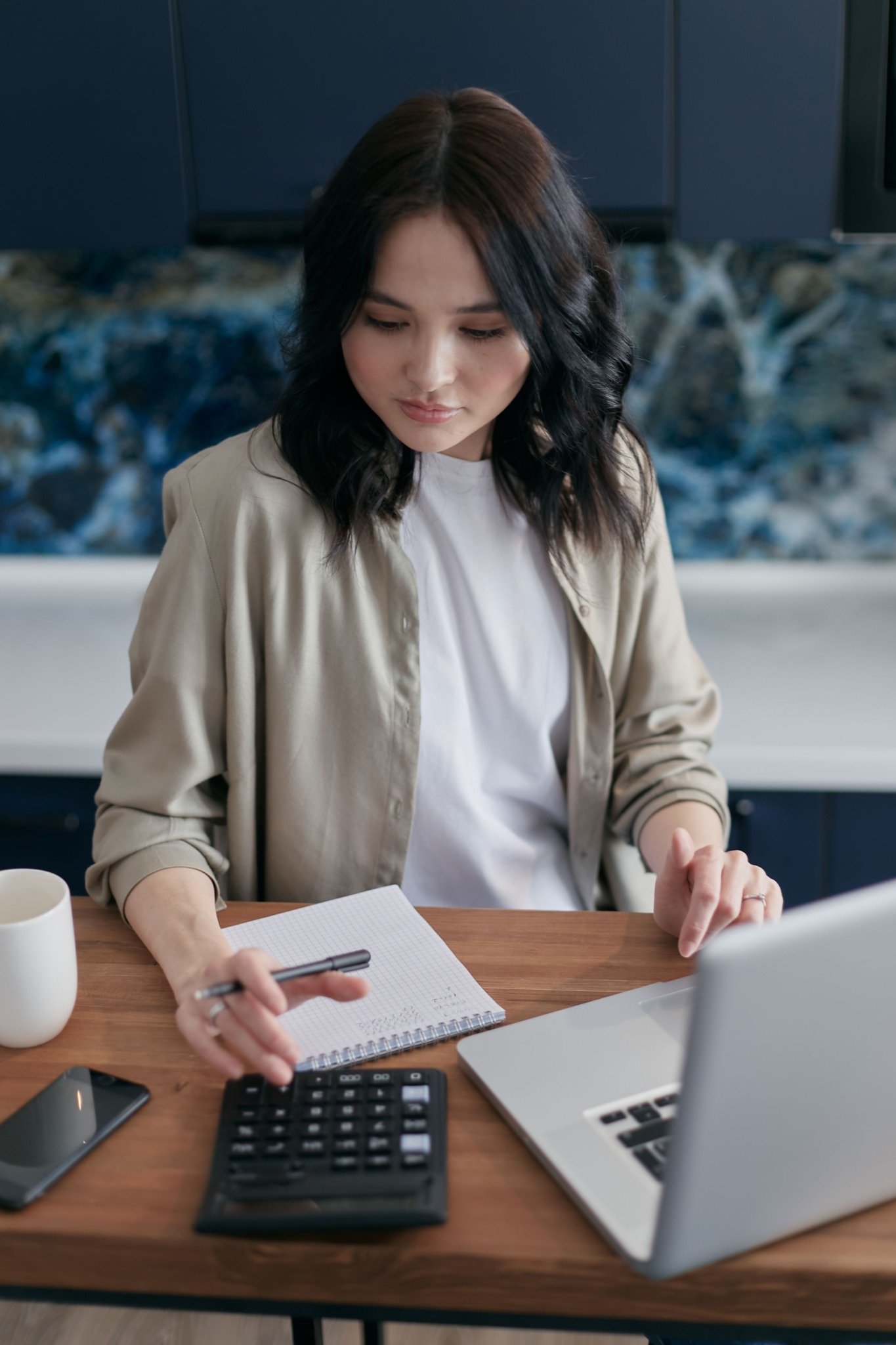 Person using a calculator while reviewing financial information on a laptop for Tahoe home buying costs