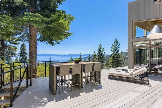 Outdoor deck with dining and bar seating overlooking Lake Tahoe.