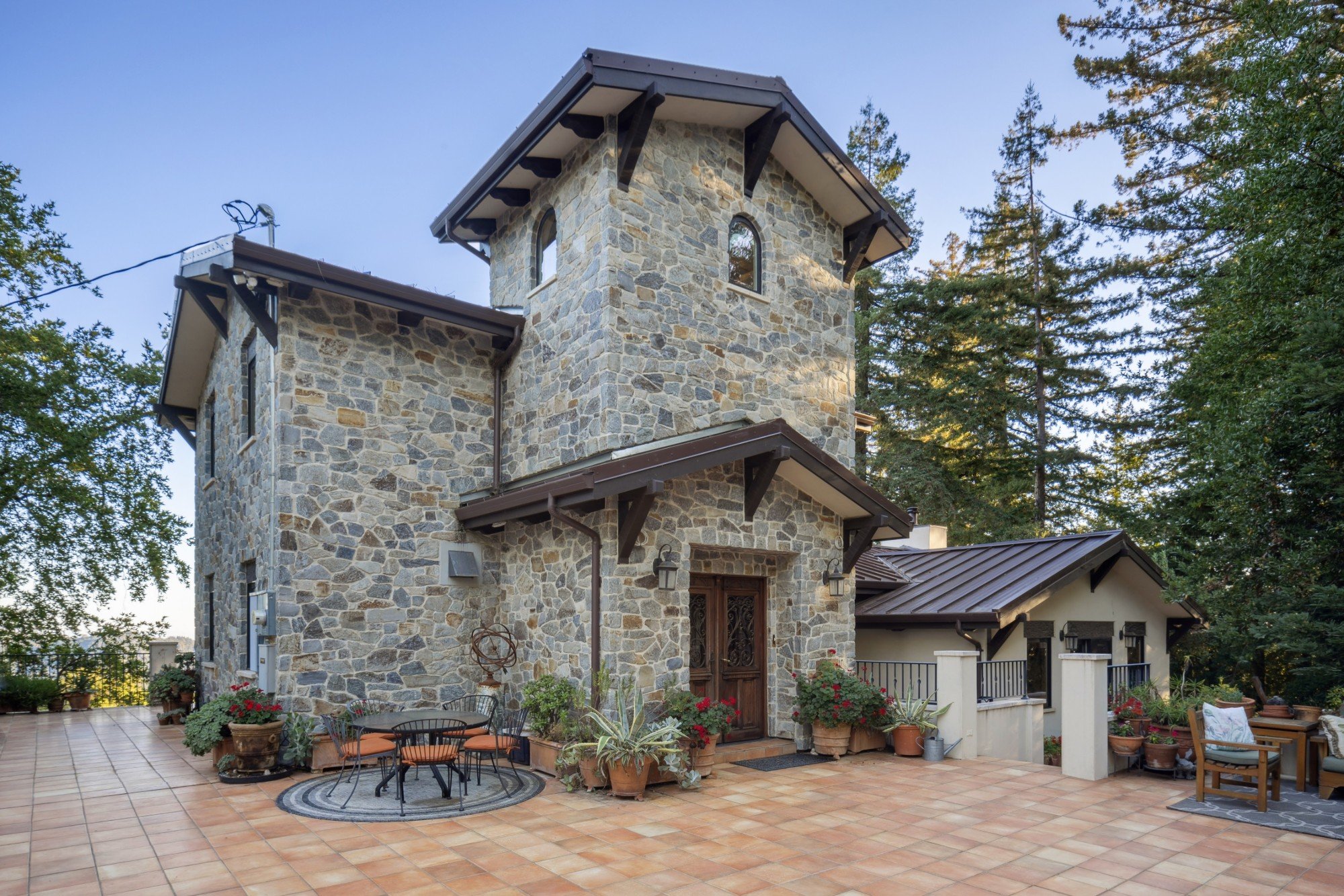 Stone-clad residence at Lago Lomita with a tower, carved wood entry doors and a tiled terrace