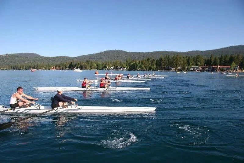 Laser and ILCA dinghies racing on Lake Tahoe with snow-covered Sierra mountains in the background.