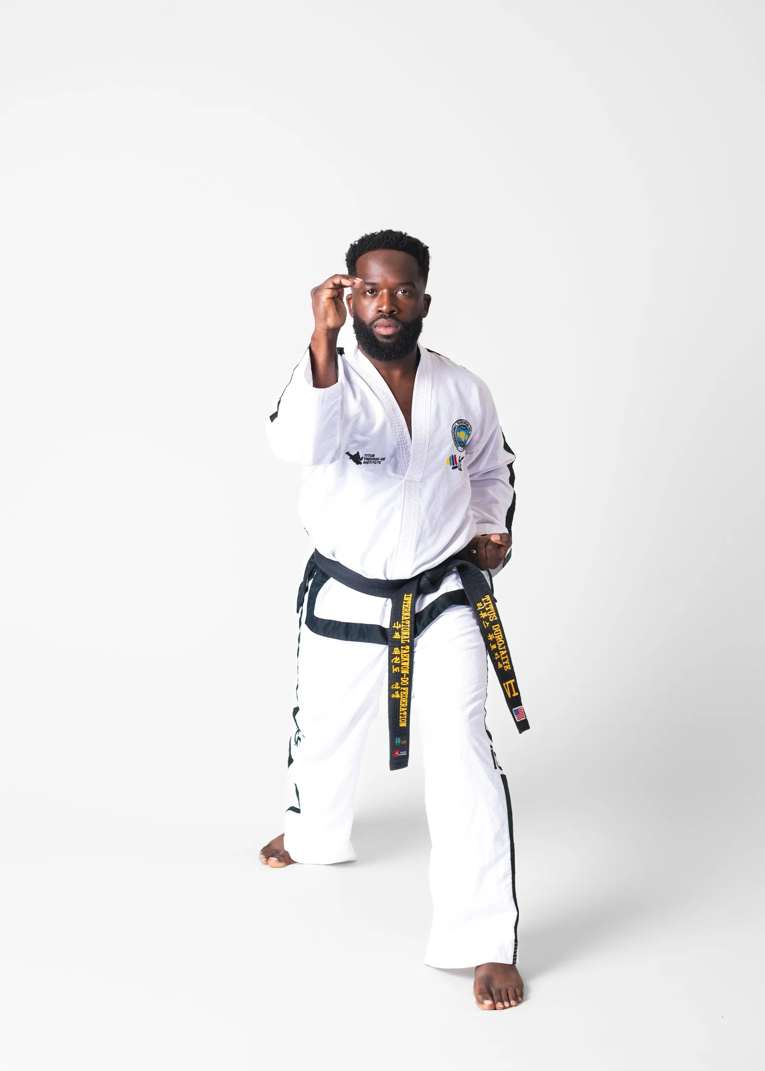 Titus Durojaiye in a sparring stance wearing a black belt Taekwon-Do uniform