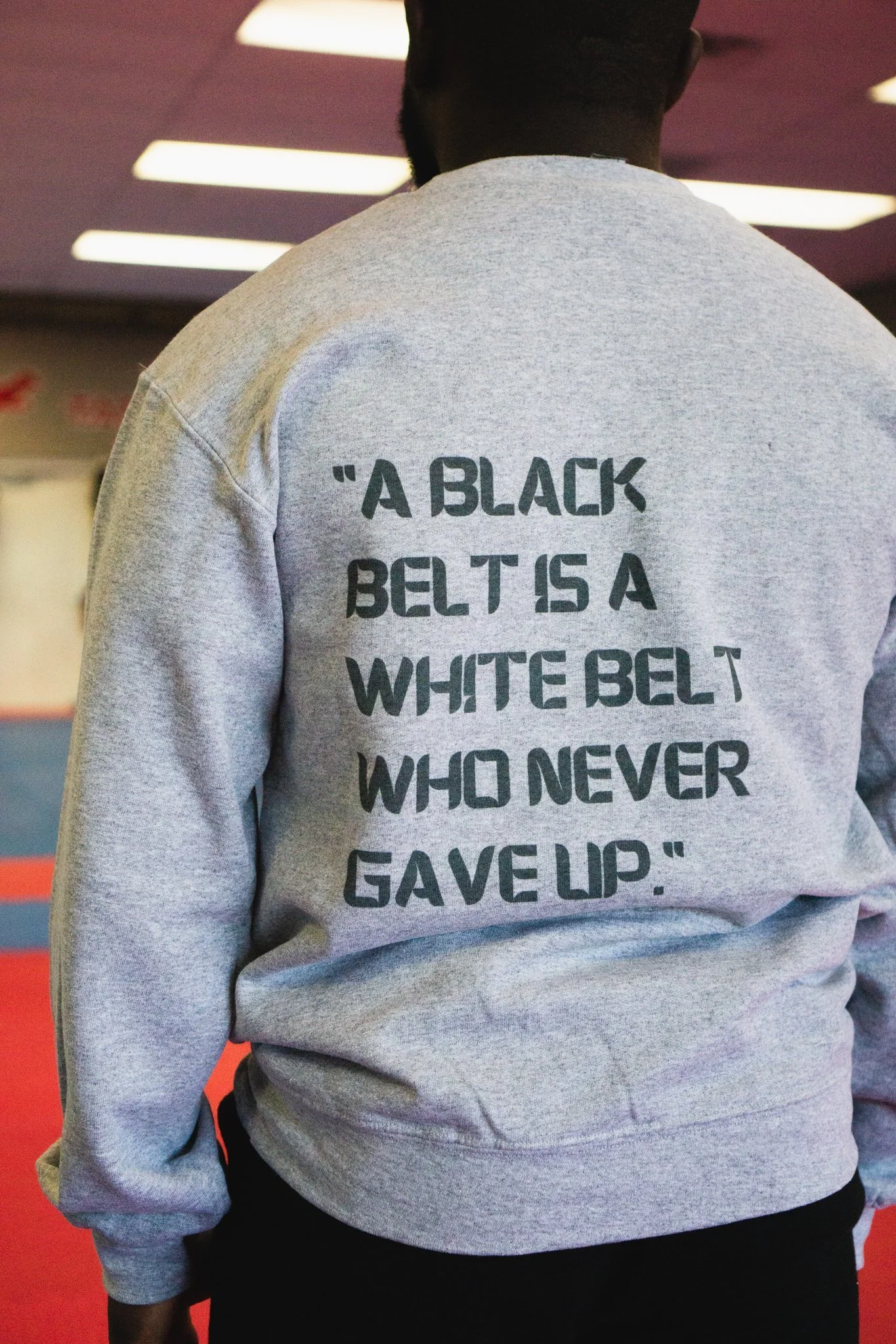A student in a sweatshirt reading, a black belt is a white belt who never gave up
