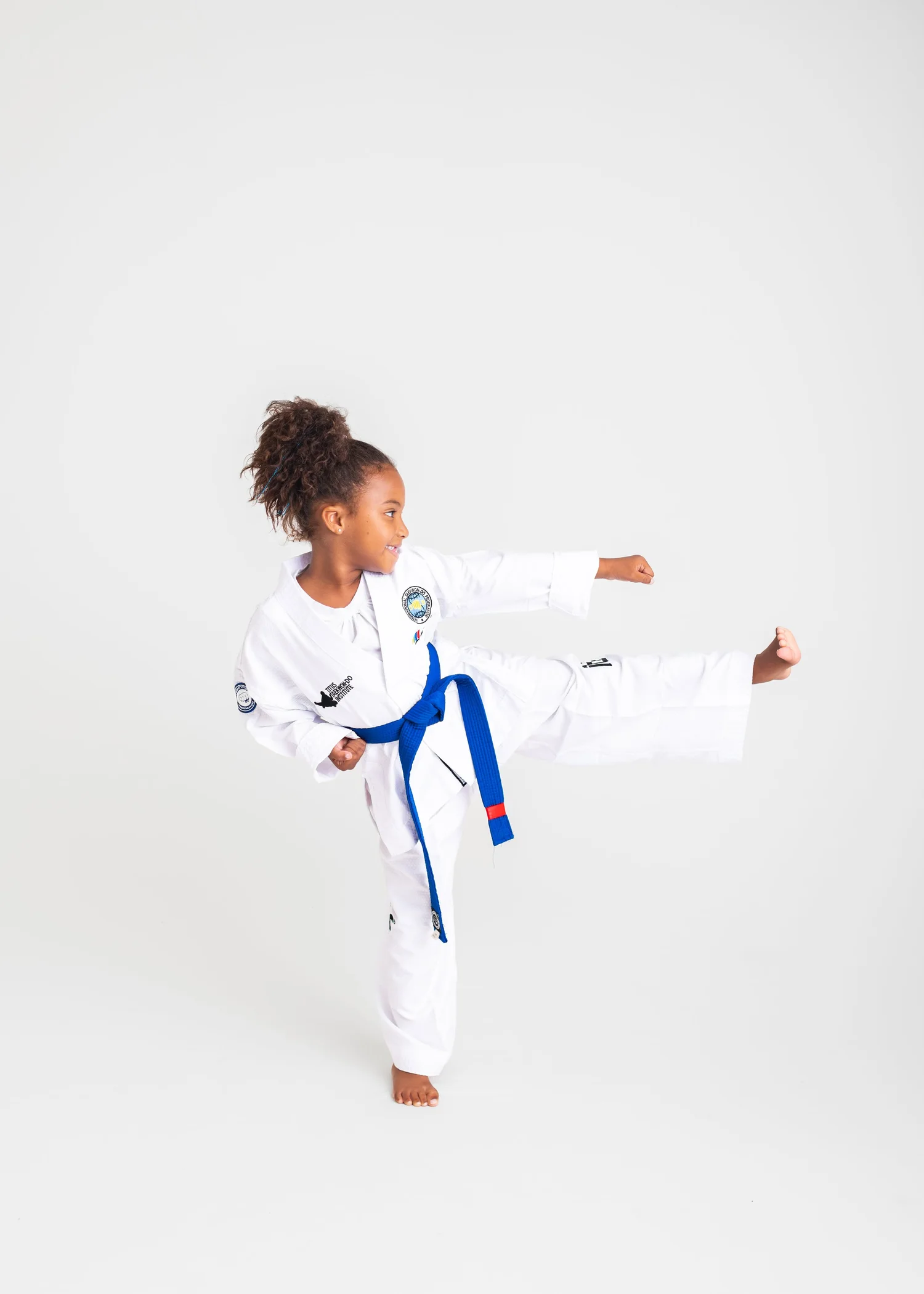 A young ITF Taekwon-Do Kids student mid side kick in a white uniform