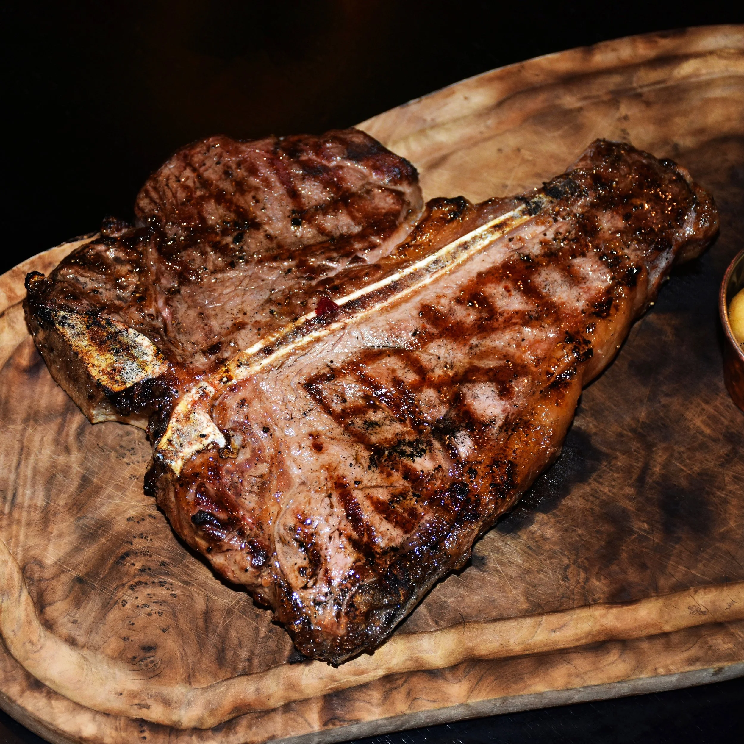 Grilled steak served on a wooden board at Branded.