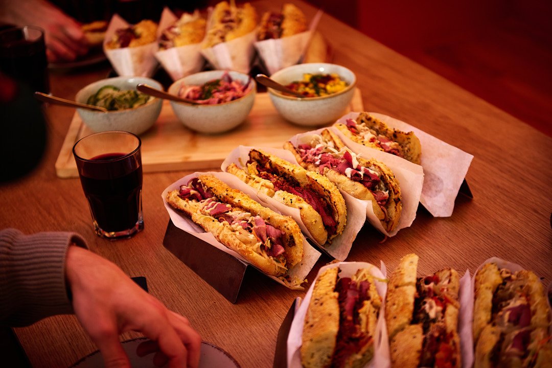 Verschiedene Sandwiches, Suppen und Getränke auf einem Holztisch bei einem Essen