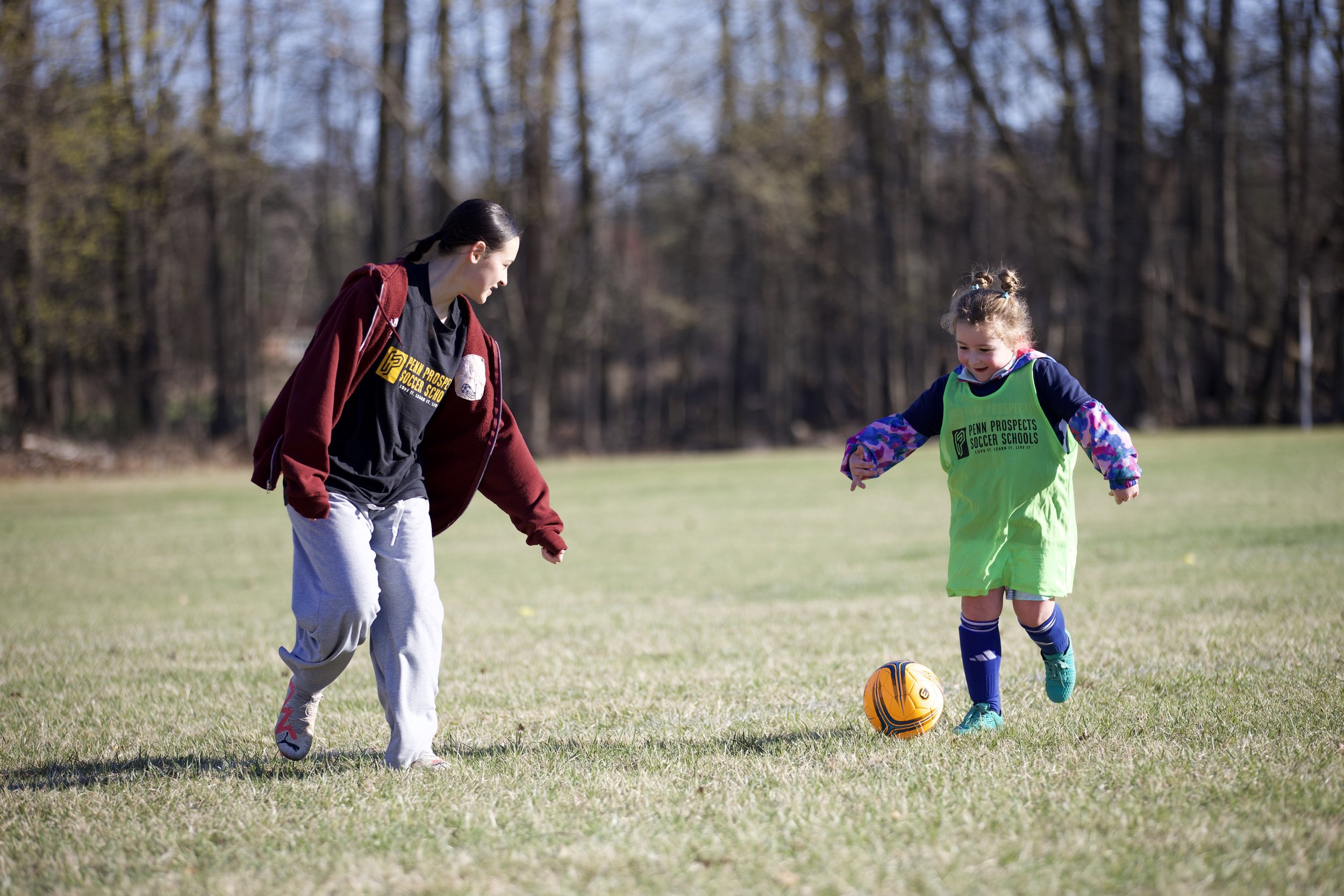 A young player keeping the ball away from volunteer soccer coach.