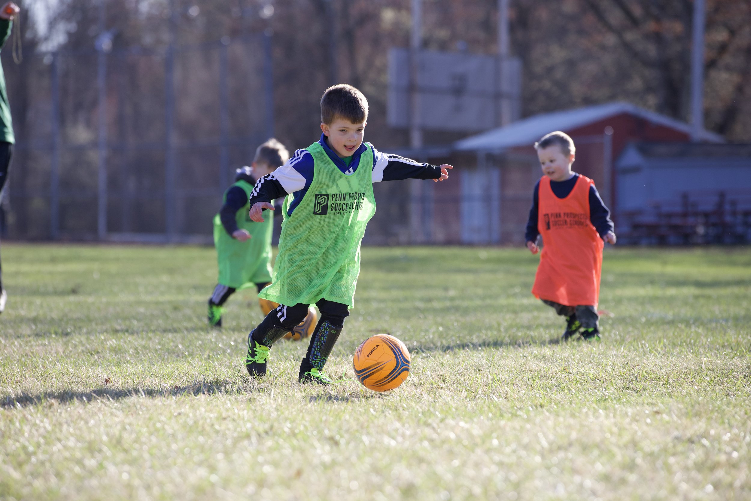 A young male soccer player running with the ball.