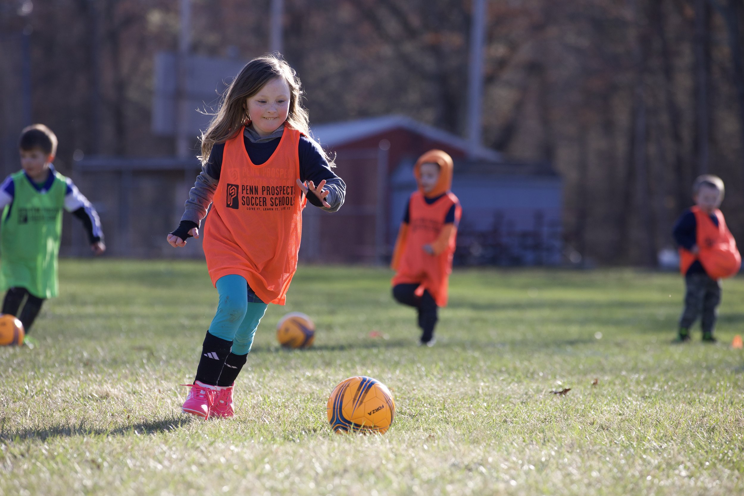 A young female soccer player smiling dribbling the ball.
