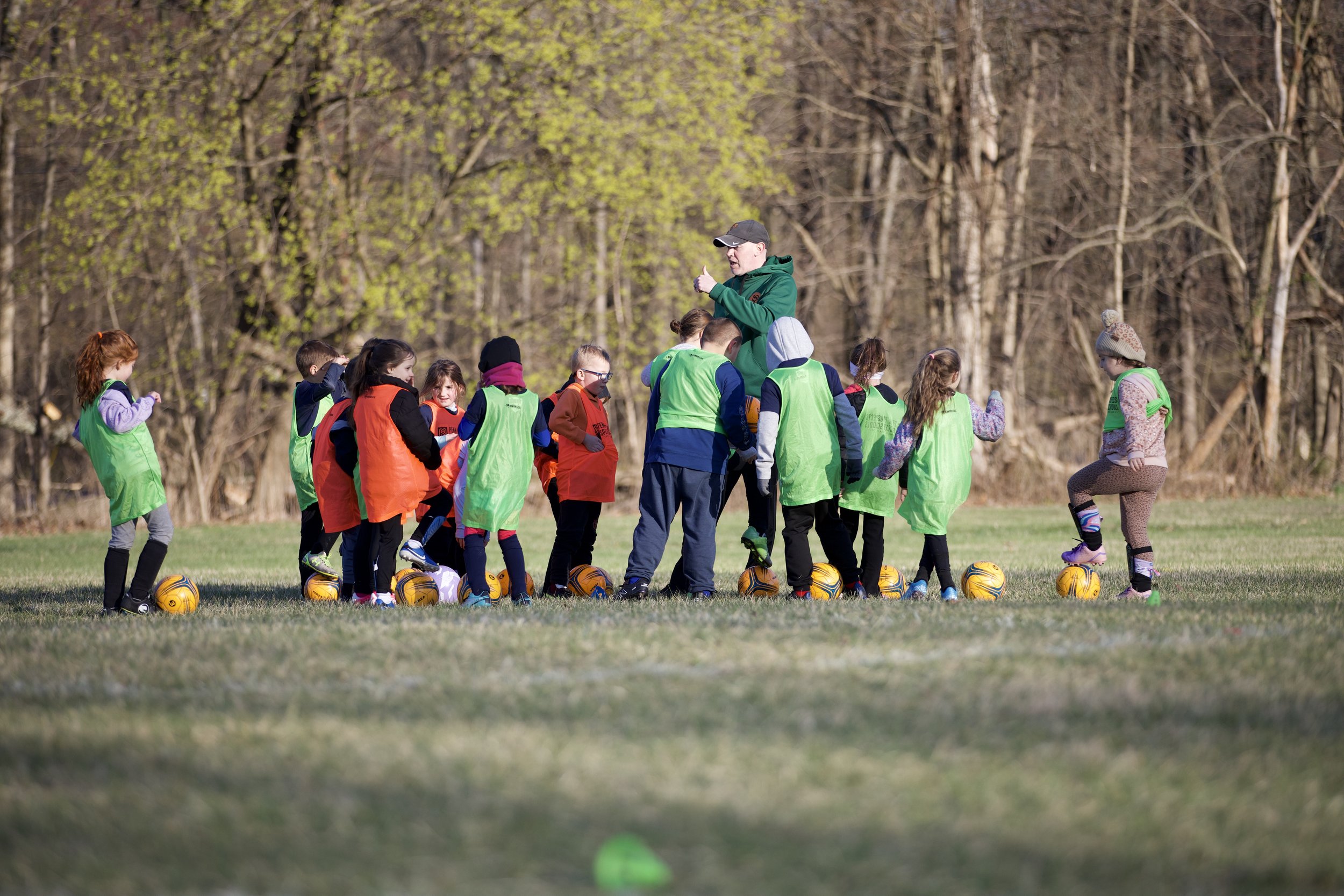 A group of young soccer players surrounding the coach waiting for instuctions.