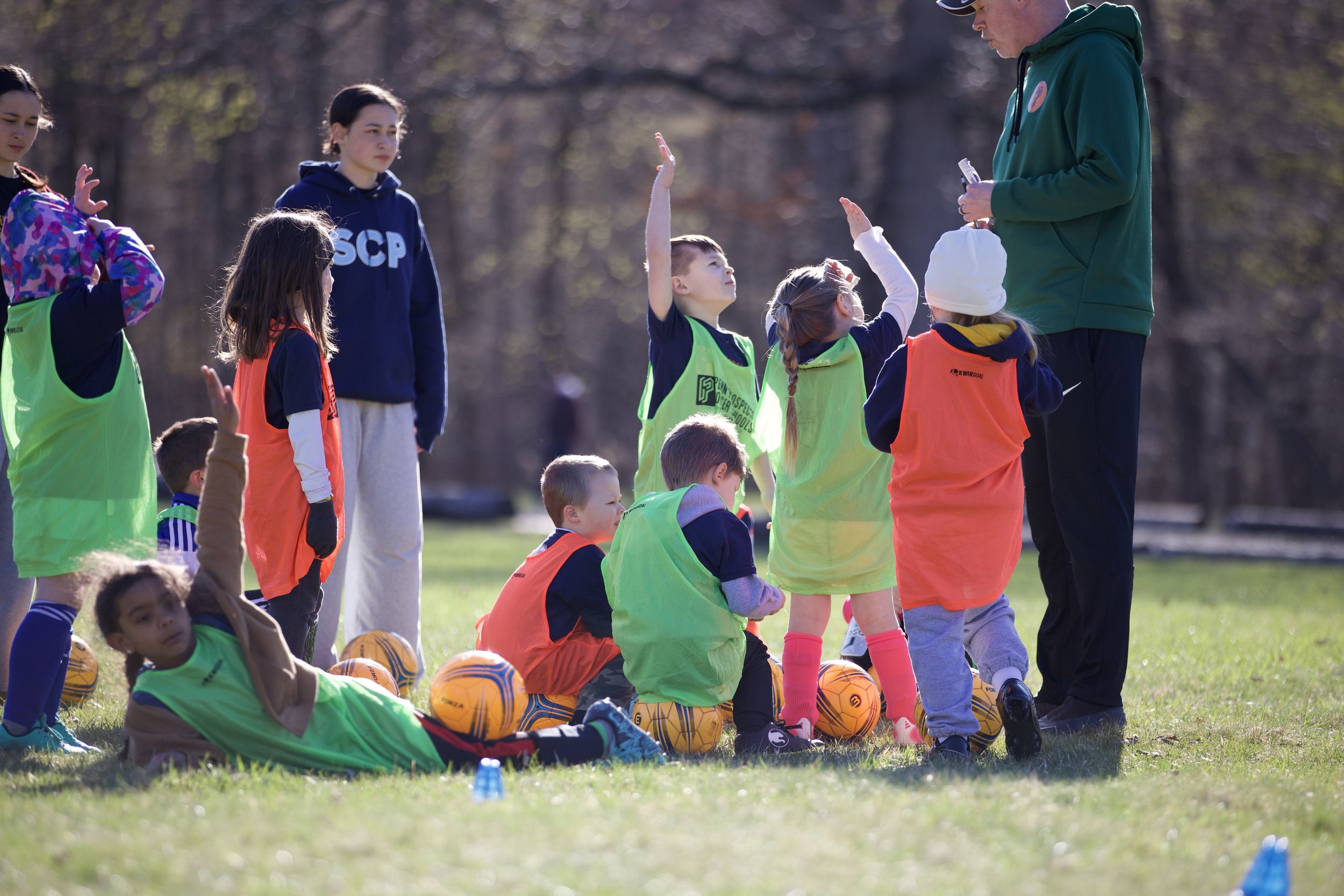 A group of young soccer players asking questions of soccer coach.
