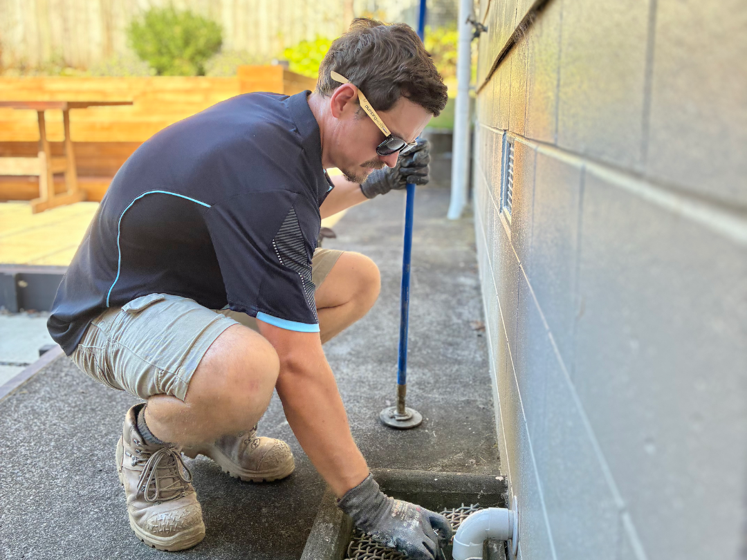 A vintage ceramic sink with black plumbing pipes against a white brick wall.