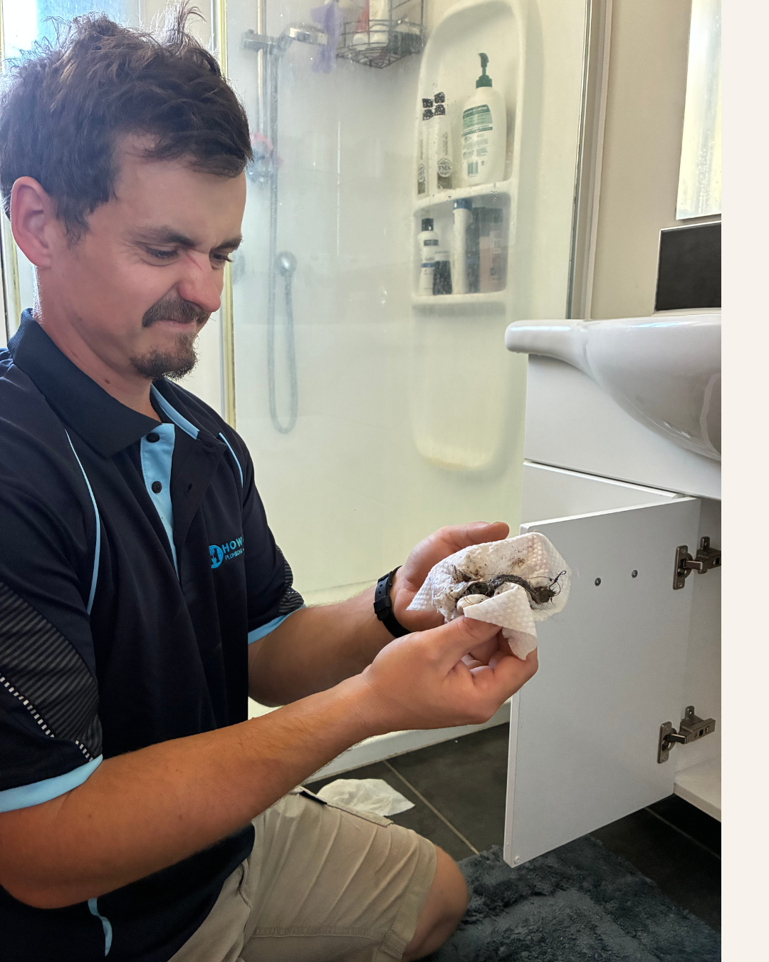 Isaac from How Good Plumbing pulling a face at a hair clog from a bathroom drain