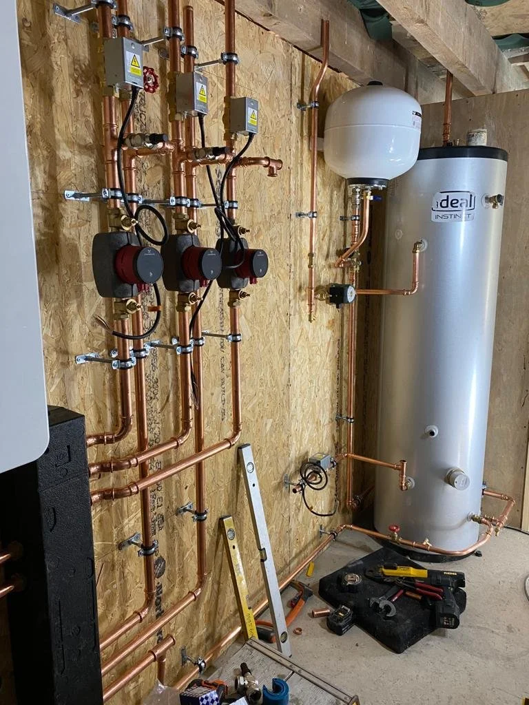 A vintage ceramic sink with black plumbing pipes against a white brick wall.