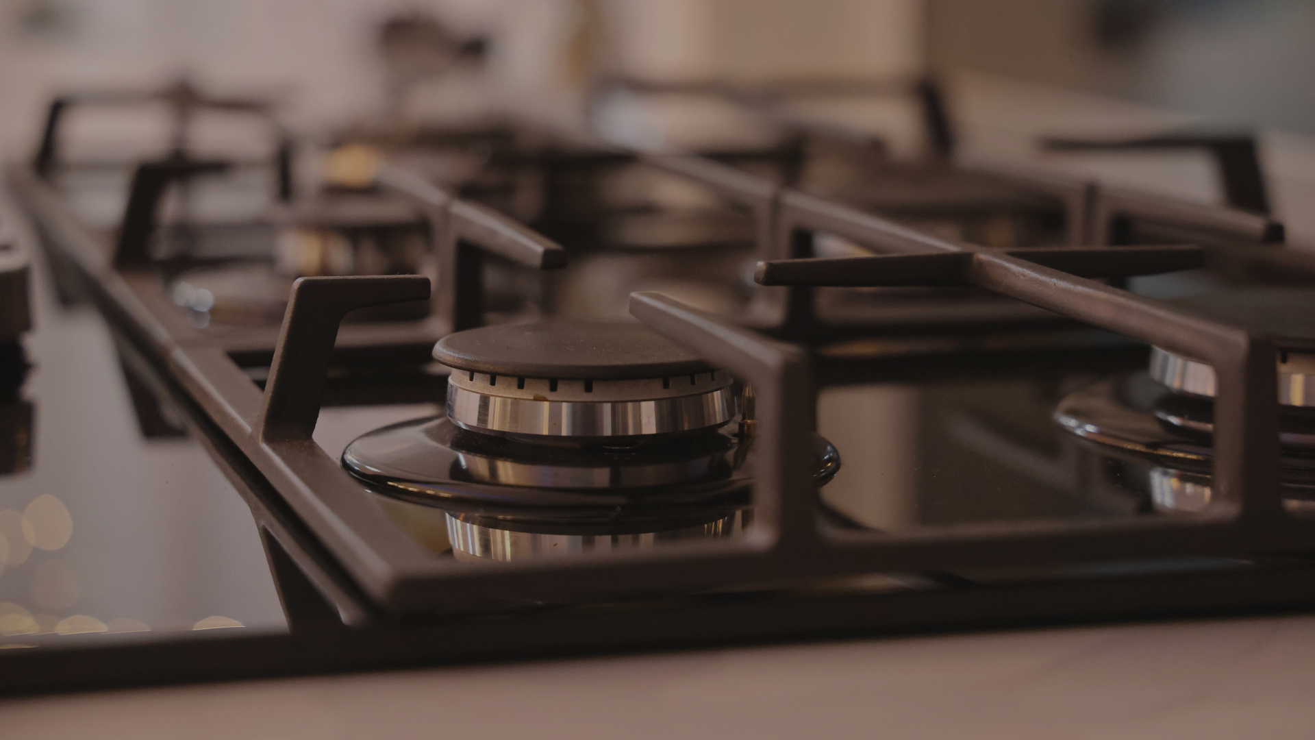Close-up of a black stovetop with gas burners, focusing on the central burner with a metal ring and black cap.