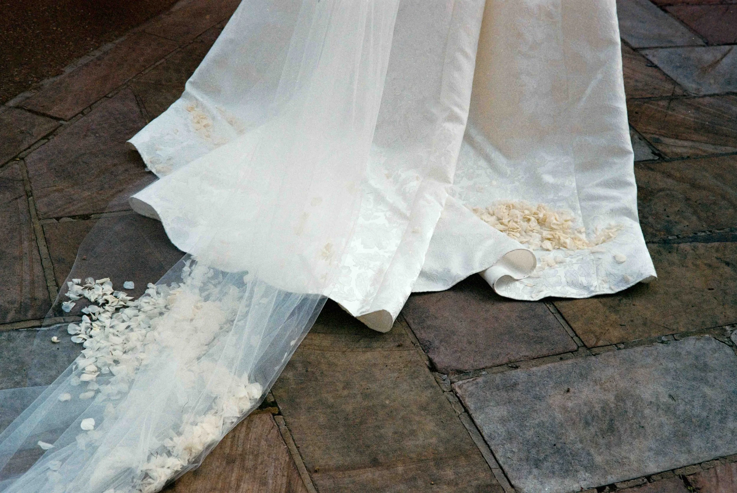 Documentary wedding photo shot on 35mm film of flower petals collected on the bride's dress and veil
