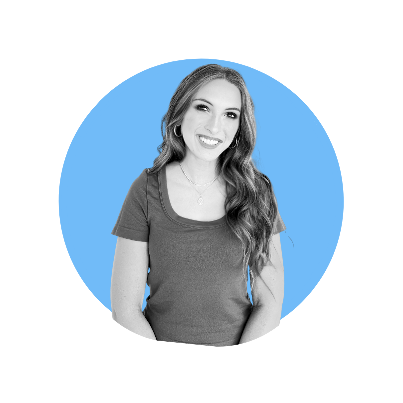 A smiling woman with long wavy hair, wearing a t-shirt and jewelry, standing in front of a blue circular background.