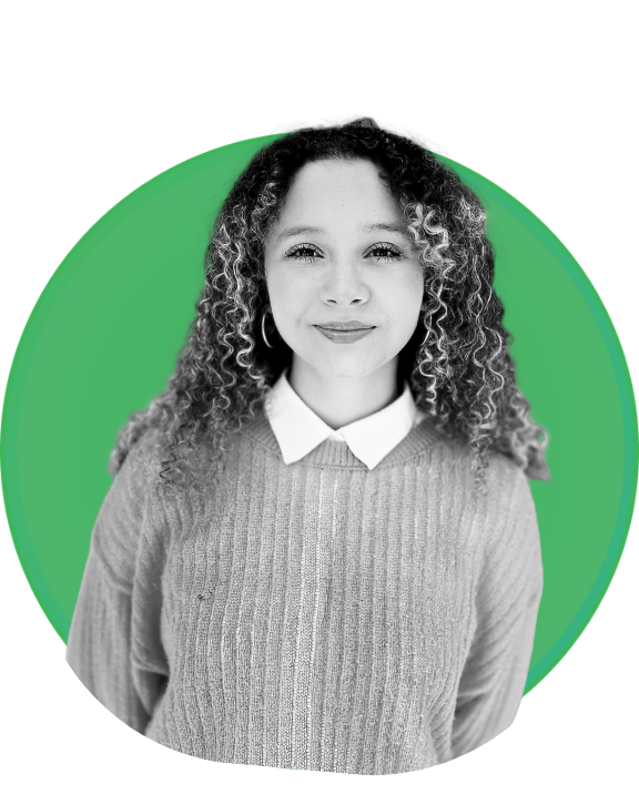 A black-and-white photo of a young woman with curly hair wearing a sweater and collared shirt, posed in front of a green circular background.