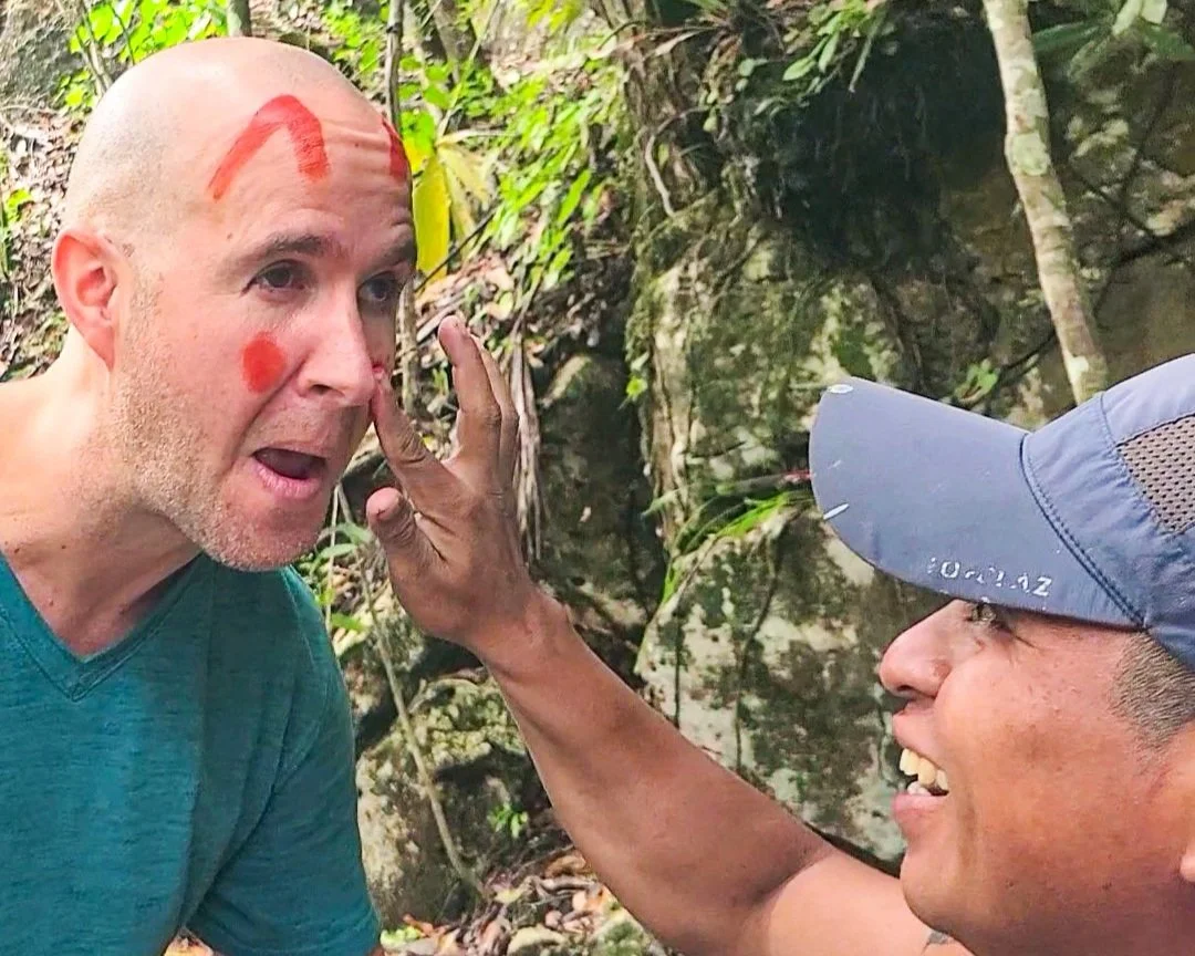 man getting Mayan face paint from a local tour guide