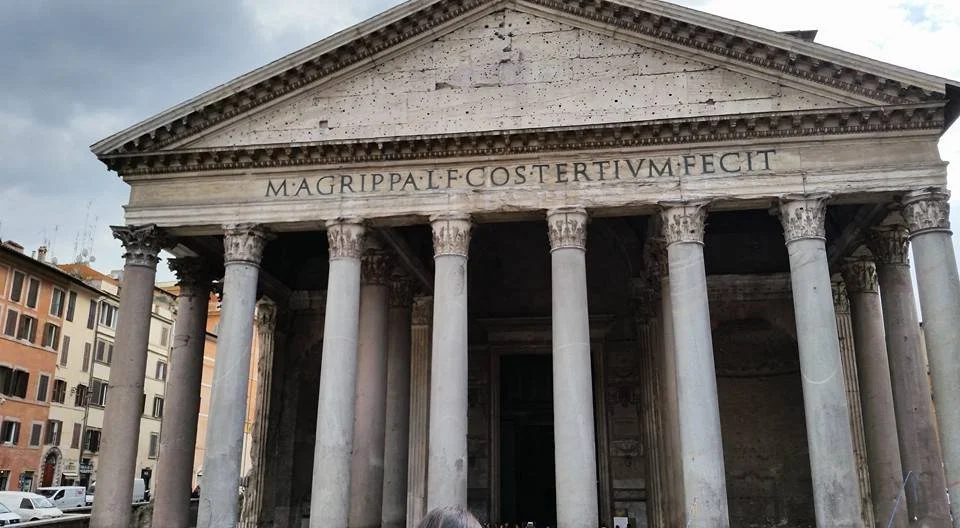 Ancient Roman temple with large marble columns and a pediment. Inscription in Latin on the frieze.