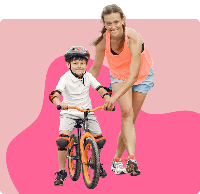 A woman helping a young boy learn to ride a bike