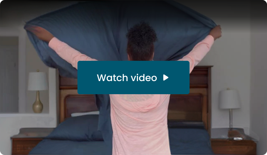 A woman shaking out a bedsheet at home. Watch video
