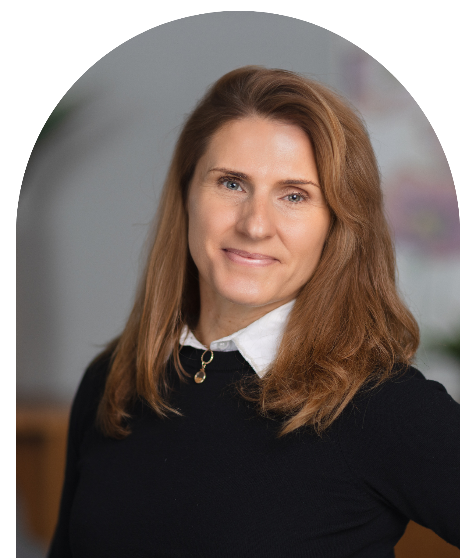 Portrait of Rachael Borlase, executive director. She has shoulder-length brown hair, wearing a white collared shirt under a black sweater, smiling.