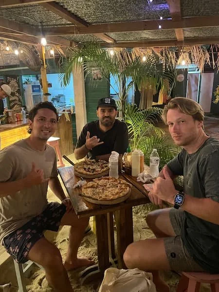 Three surfers enjoying pizza and tacos night dinner during The Experience Surf Camp at Bocas del Toro Panama