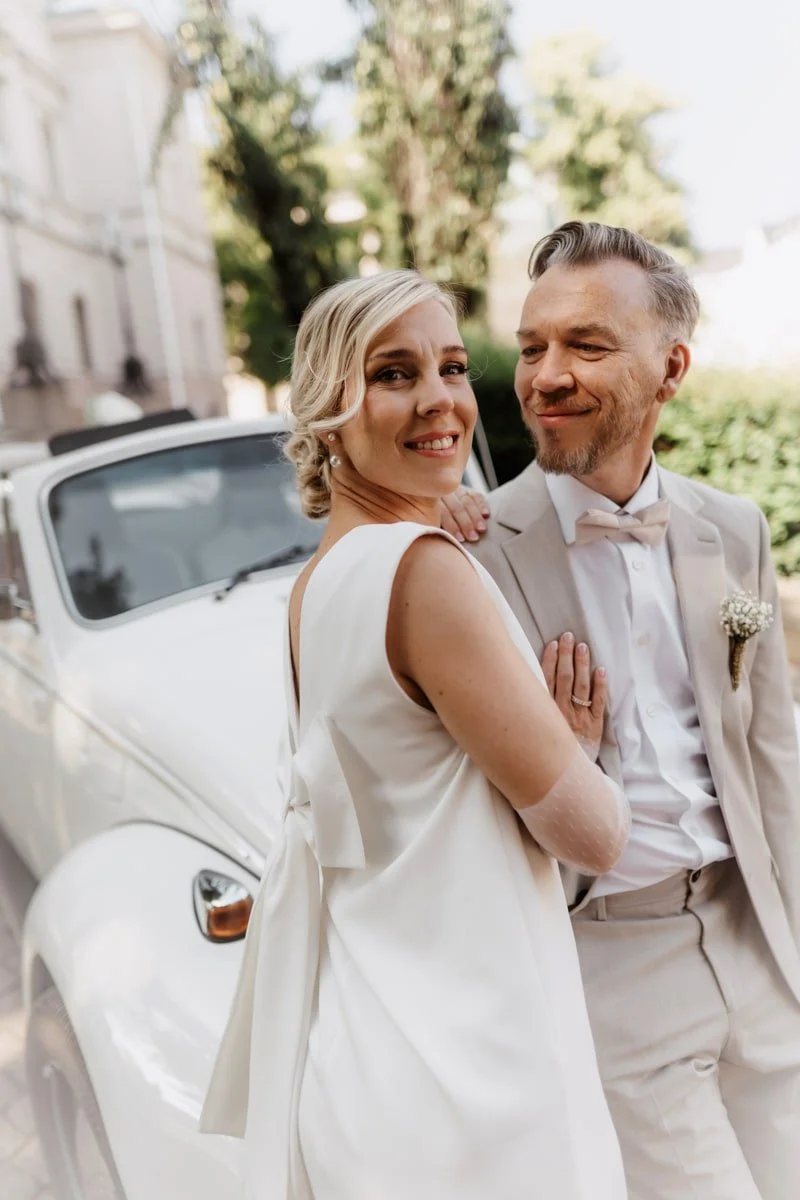 tyylikäs hääpari ja valkoinen hää-auto