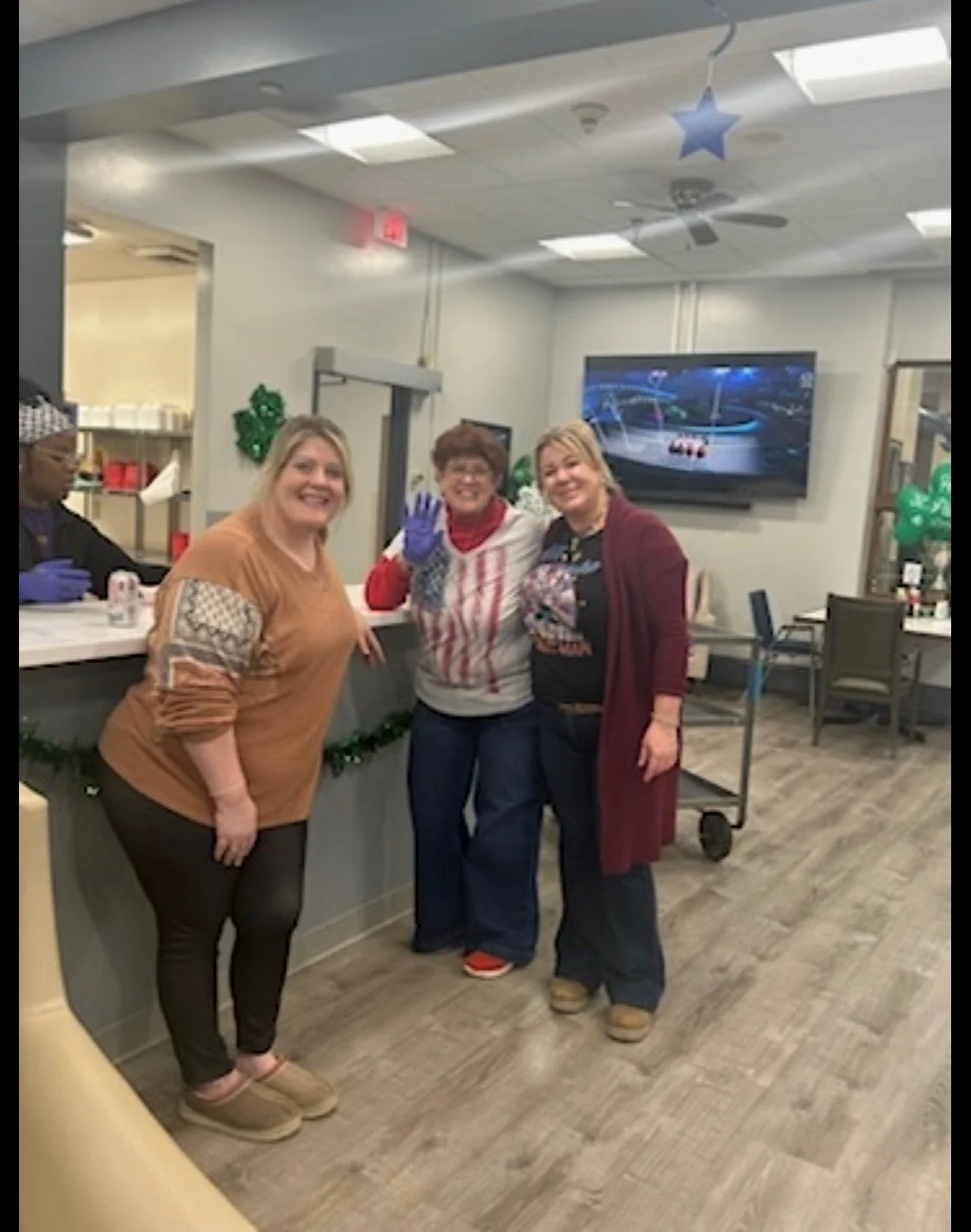 Three women standing inside a room decorated for Christmas, with one wearing a 'Team USA' shirt, smiling and posing for the camera.