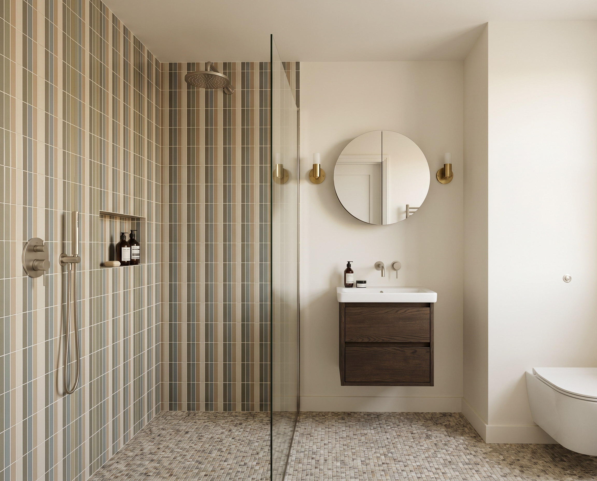 Modern bathroom with a glass-enclosed shower, beige and brown vertical striped tiles, and a circular mirror above a small vanity with dark wood drawers. There are brass wall sconces on either side of the mirror, and a sleek white toilet is in the cor