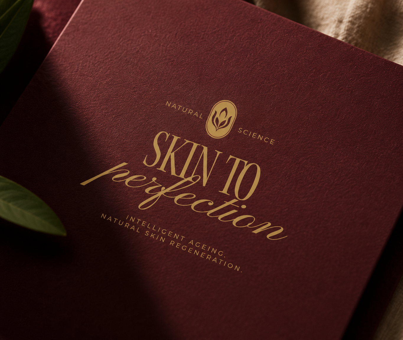 Skin to Perfection luxury brand identity with a gold logo on textured burgundy stationery.