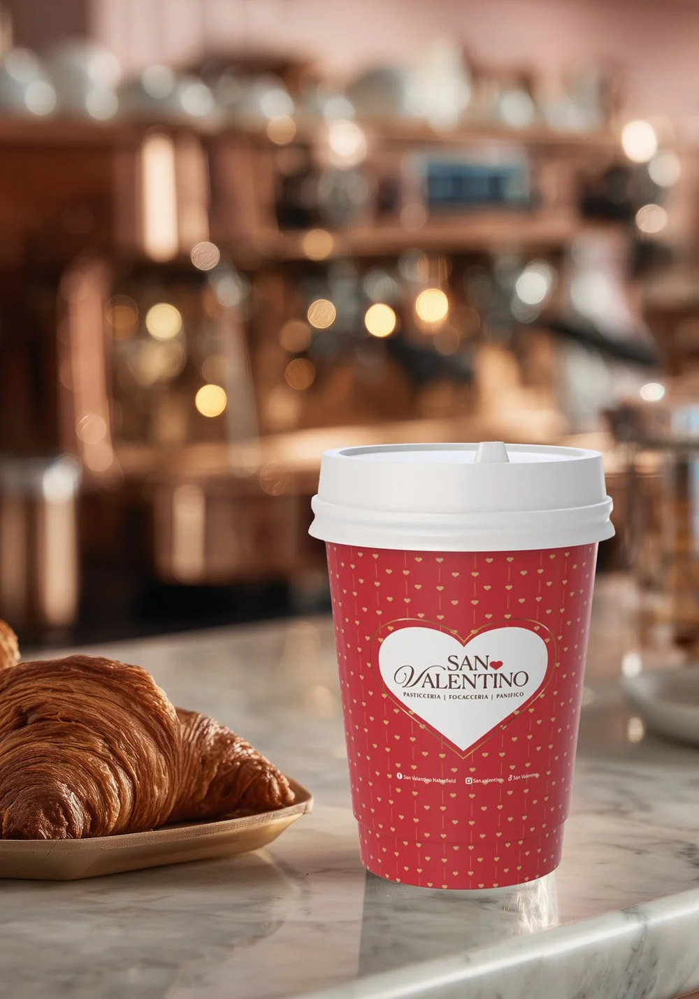 San Valentino Pasticceria branded coffee cup mockup featuring a red takeaway cup with heart logo, café counter styling and croissant.