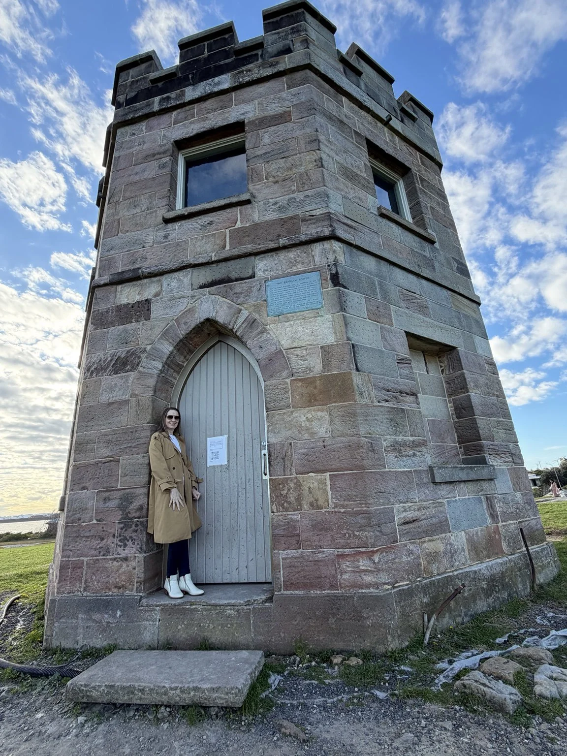 Woman near a weathered sandstone building at La Perouse, Sydney, surrounded by the coastal landscape.