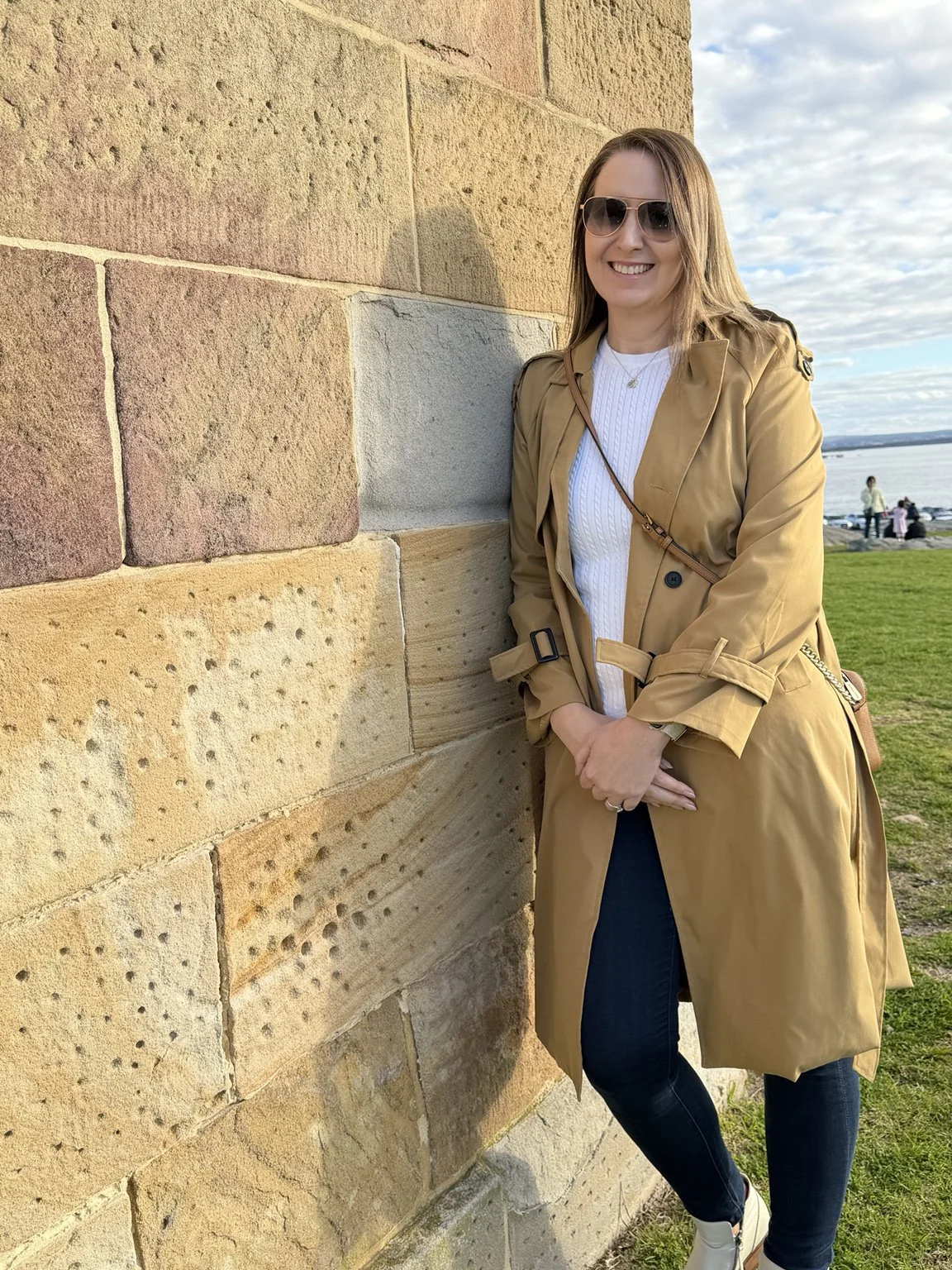 Woman leaning against a weathered sandstone wall at La Perouse, Sydney.