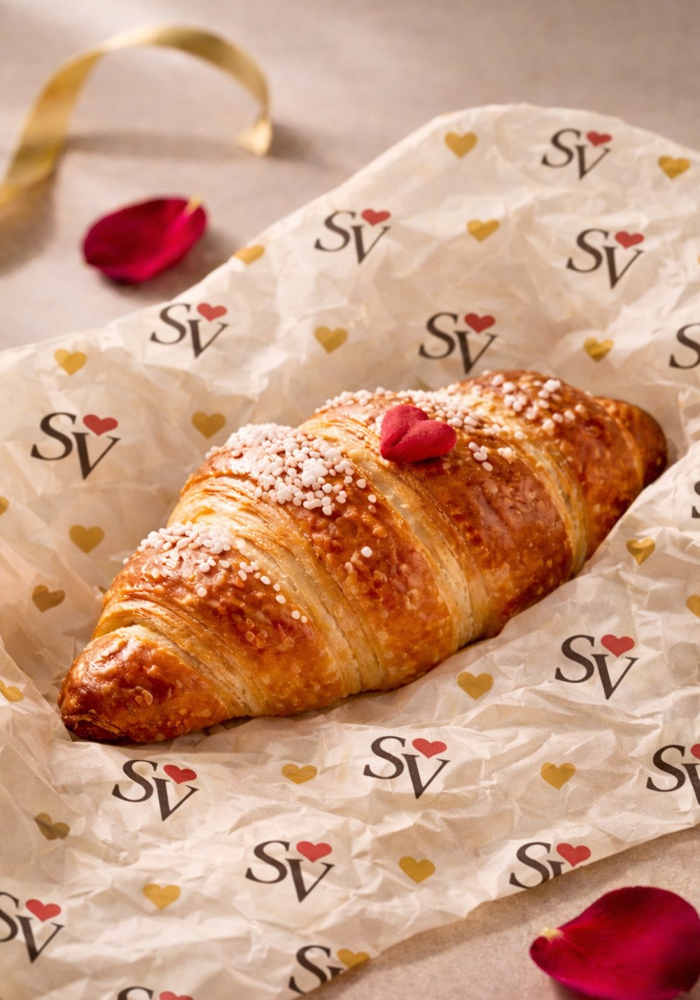 San Valentino Pasticceria branded wrapping paper mockup featuring a croissant on custom SV heart-patterned tissue paper with warm pastry styling.