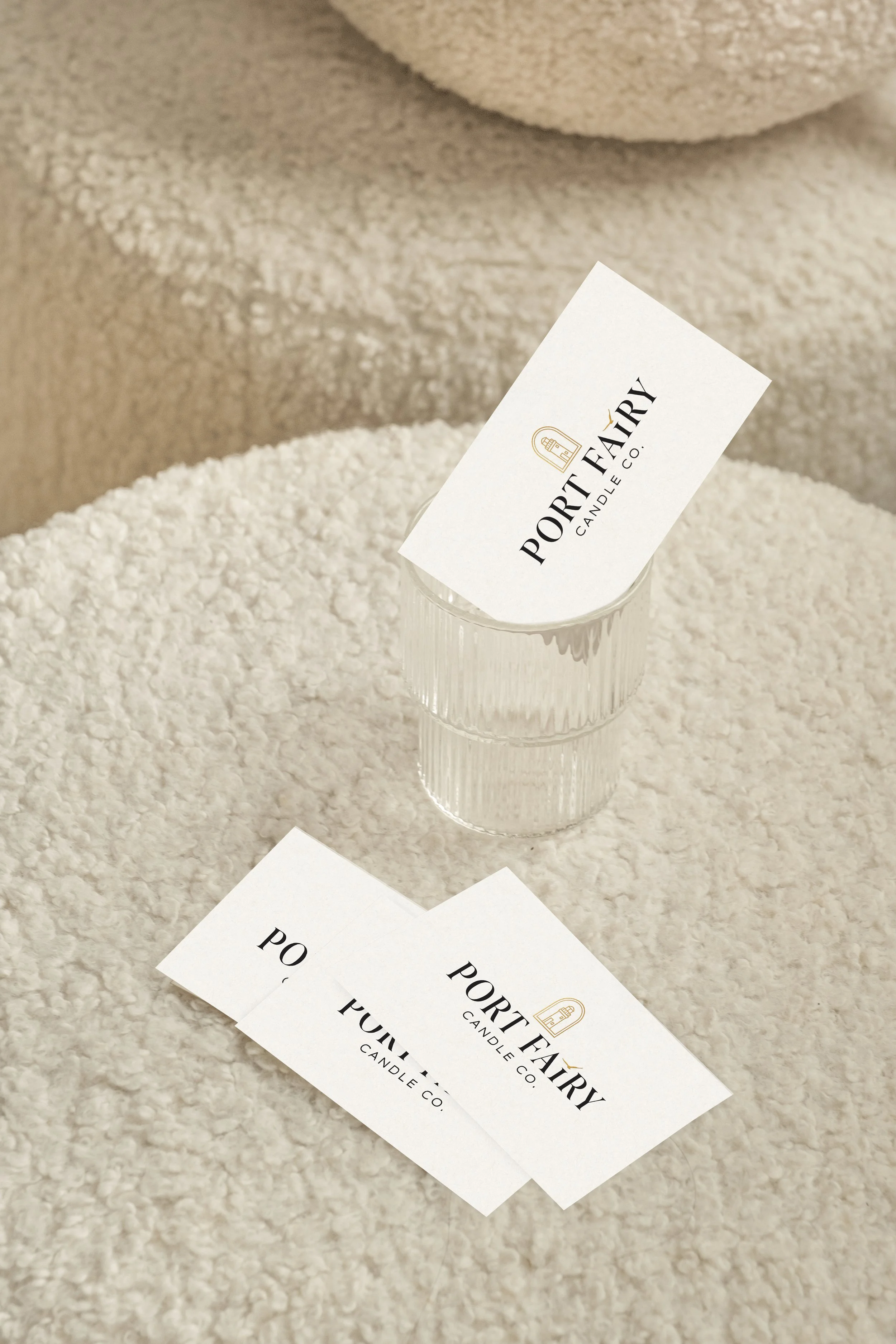 Port Fairy Candle Co. business card mockup featuring minimal cream cards with black and gold logo details styled on soft textured fabric.