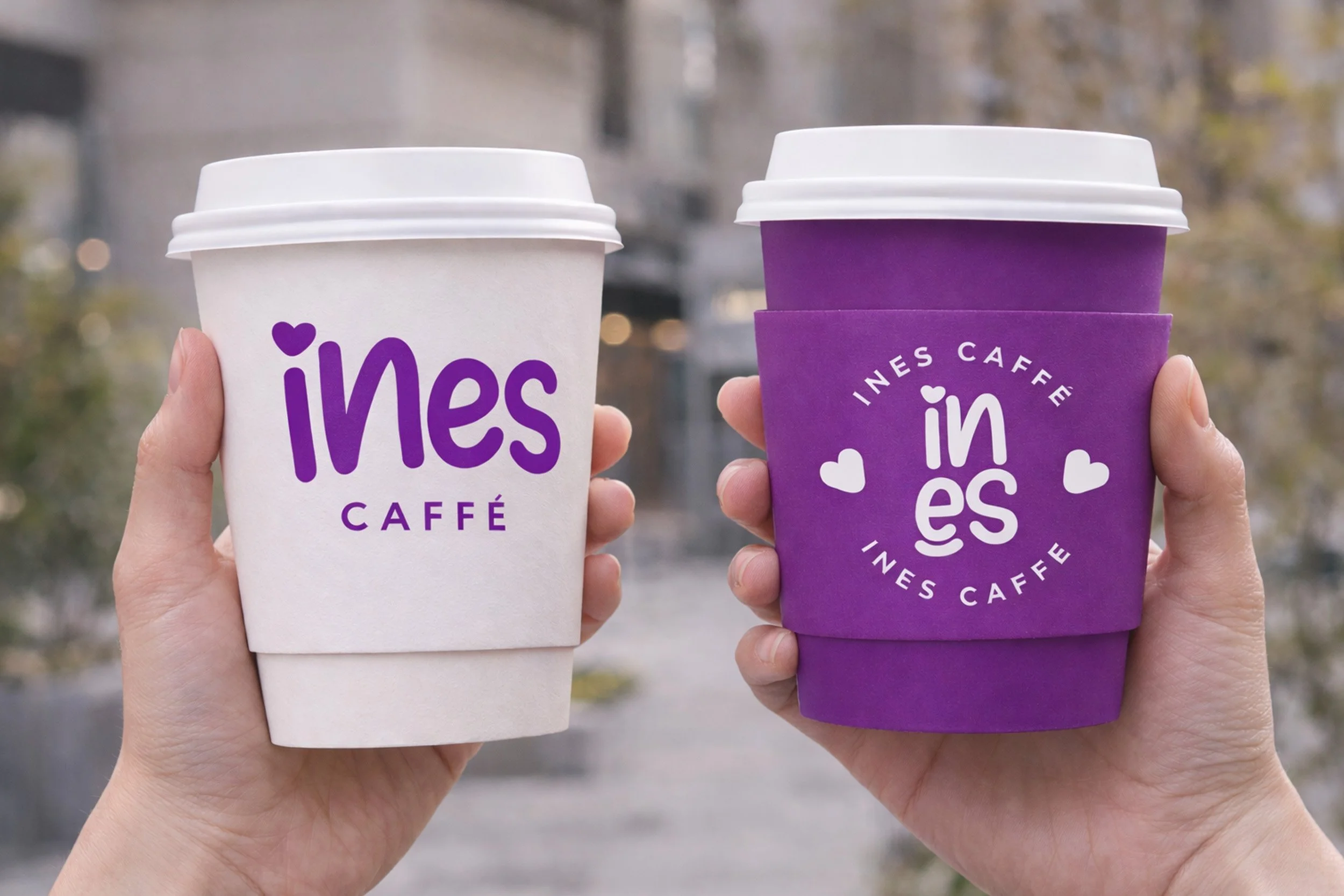 Ines Caffe takeaway coffee cups mockup featuring white and purple branded cups held outdoors with playful café logo design.
