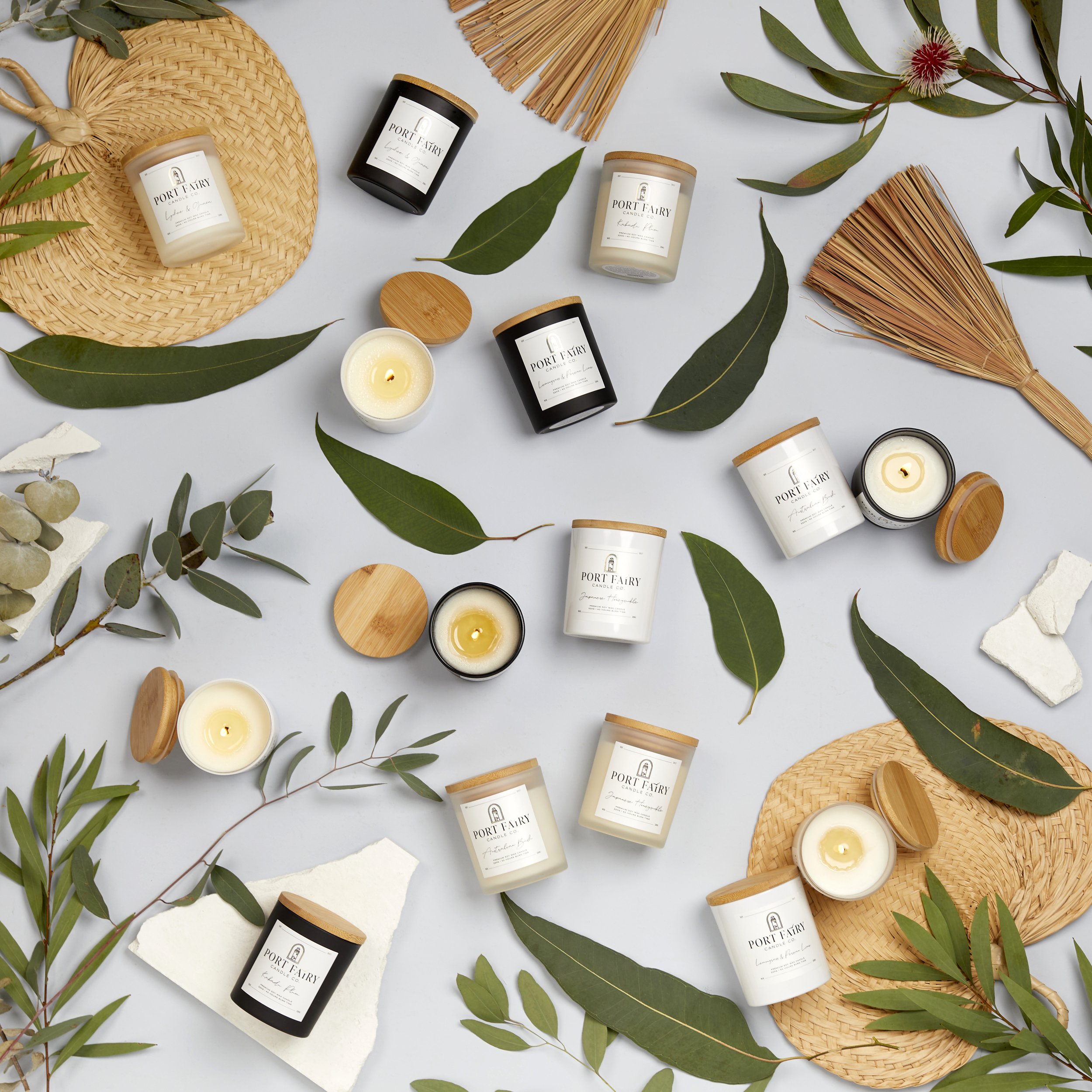 Port Fairy Candle Co. product flat lay featuring branded candles with bamboo lids, eucalyptus leaves, natural textures and soft lifestyle styling.