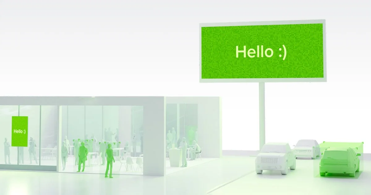 A digital rendering of a modern building with large glass windows, showing people inside. The exterior features a large green sign with white text that reads 'Hello :)'. There are three cars parked outside, and a large green digital billboard also di