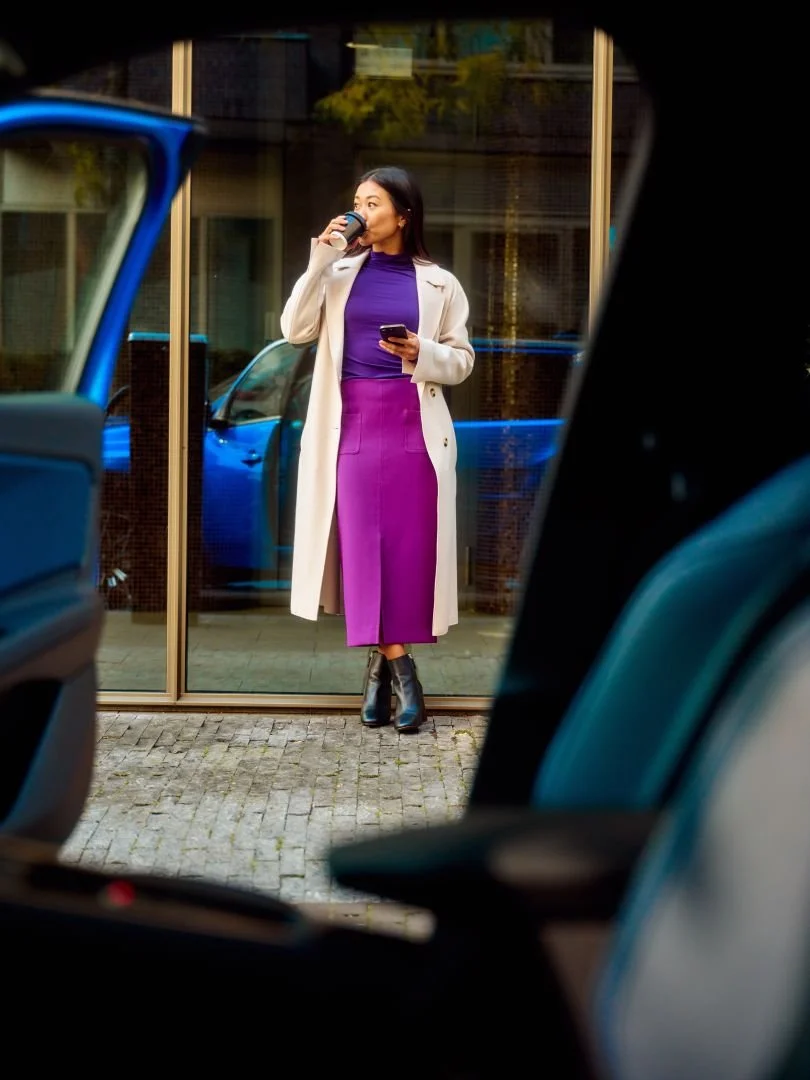 Woman drinking coffee while her car charges, Athlon Car Lease shoot in Amsterdam